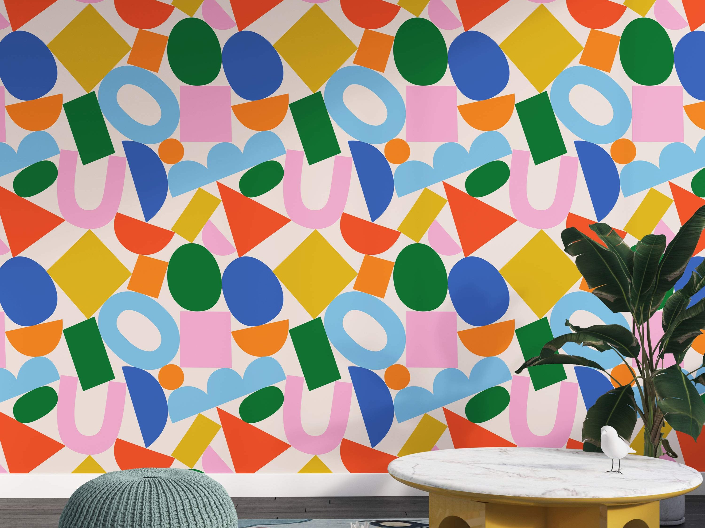 Wallpaper with a playful abstract pattern of scattered geometric shapes in bright blue, green, yellow, orange, and pink.