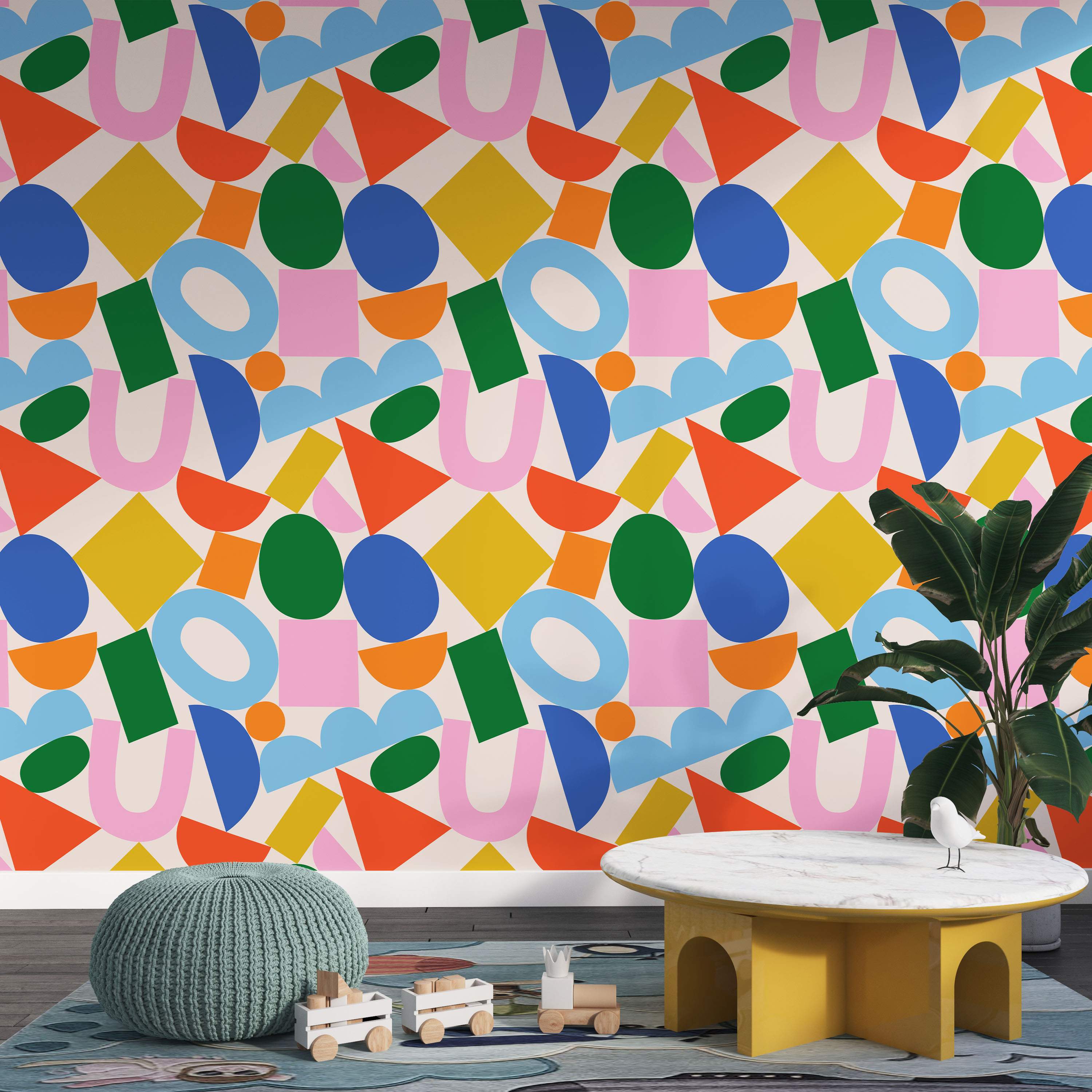 Wallpaper with a playful abstract pattern of scattered geometric shapes in bright blue, green, yellow, orange, and pink.