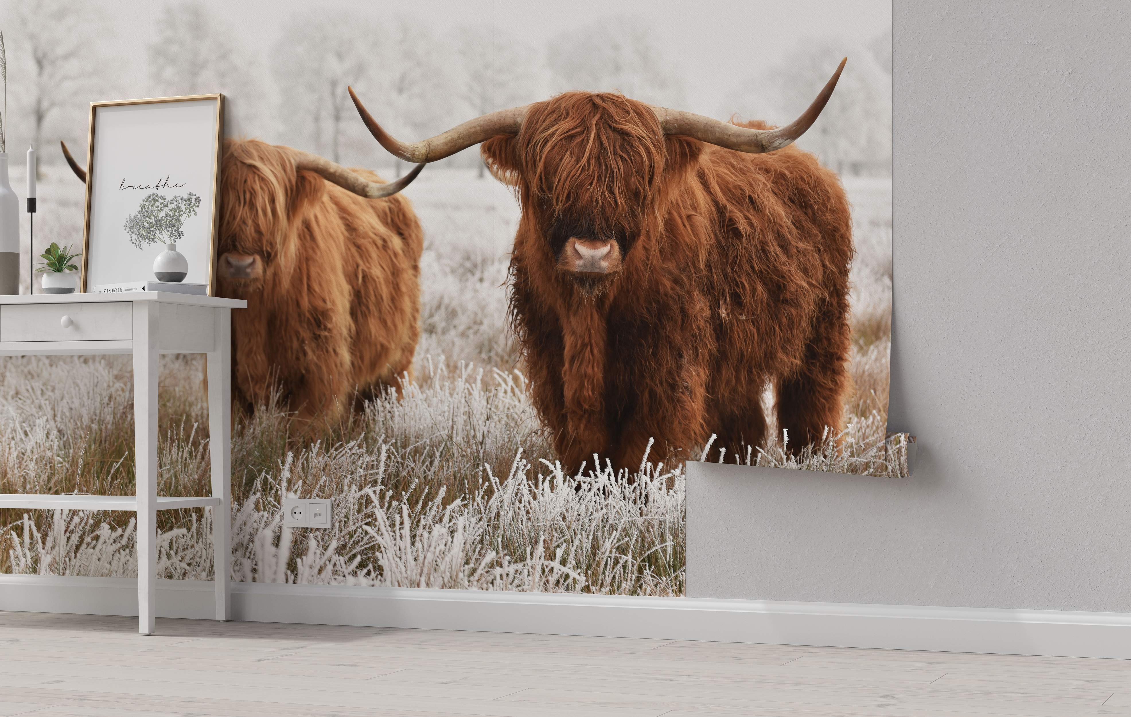 Mural depicting two brown Highland cows with long horns standing in a frosty, white field during winter.