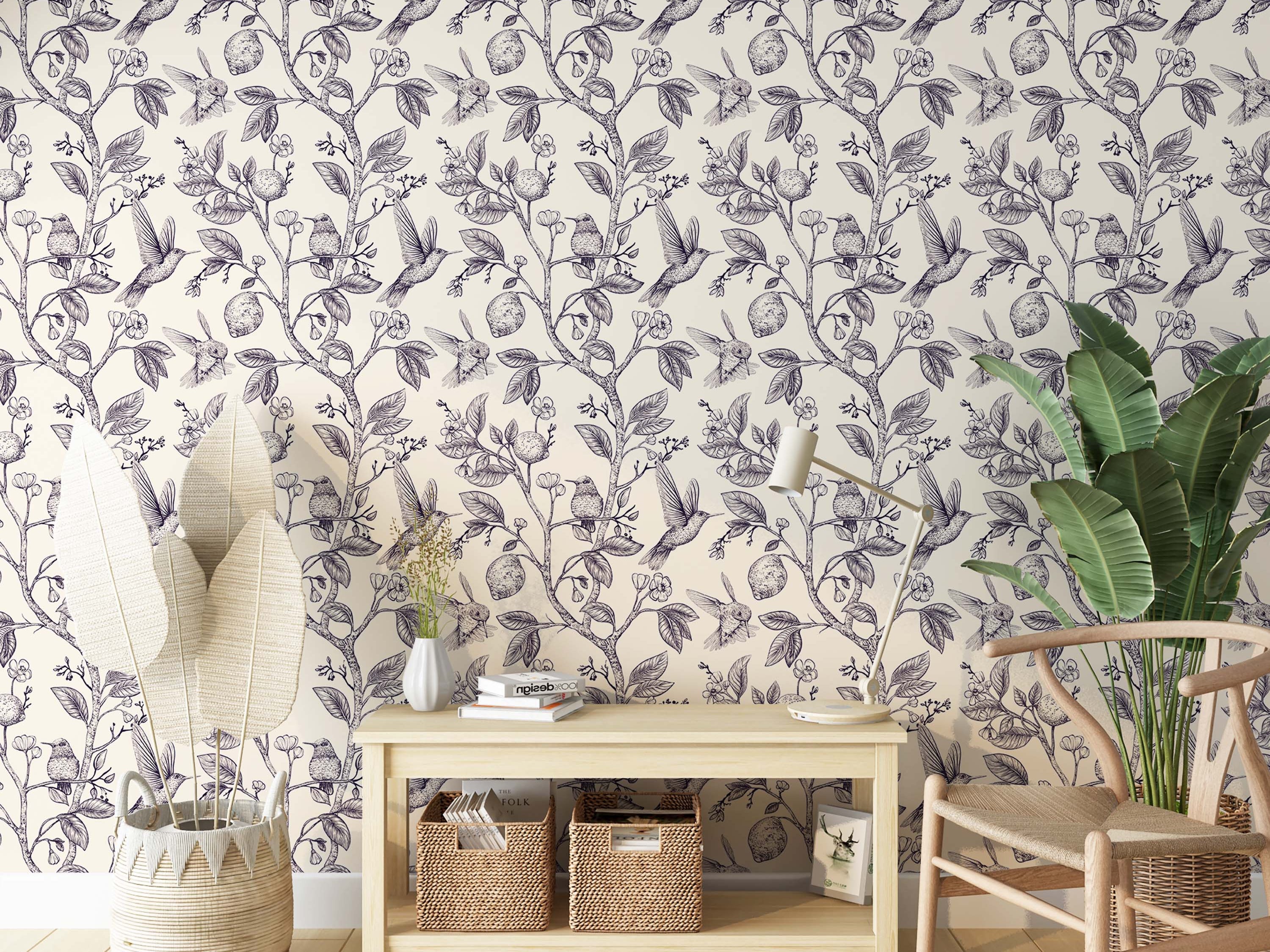 Wallpaper with a navy blue sketch-style pattern of hummingbirds, lemons, and flowers on branches, over a cream background.