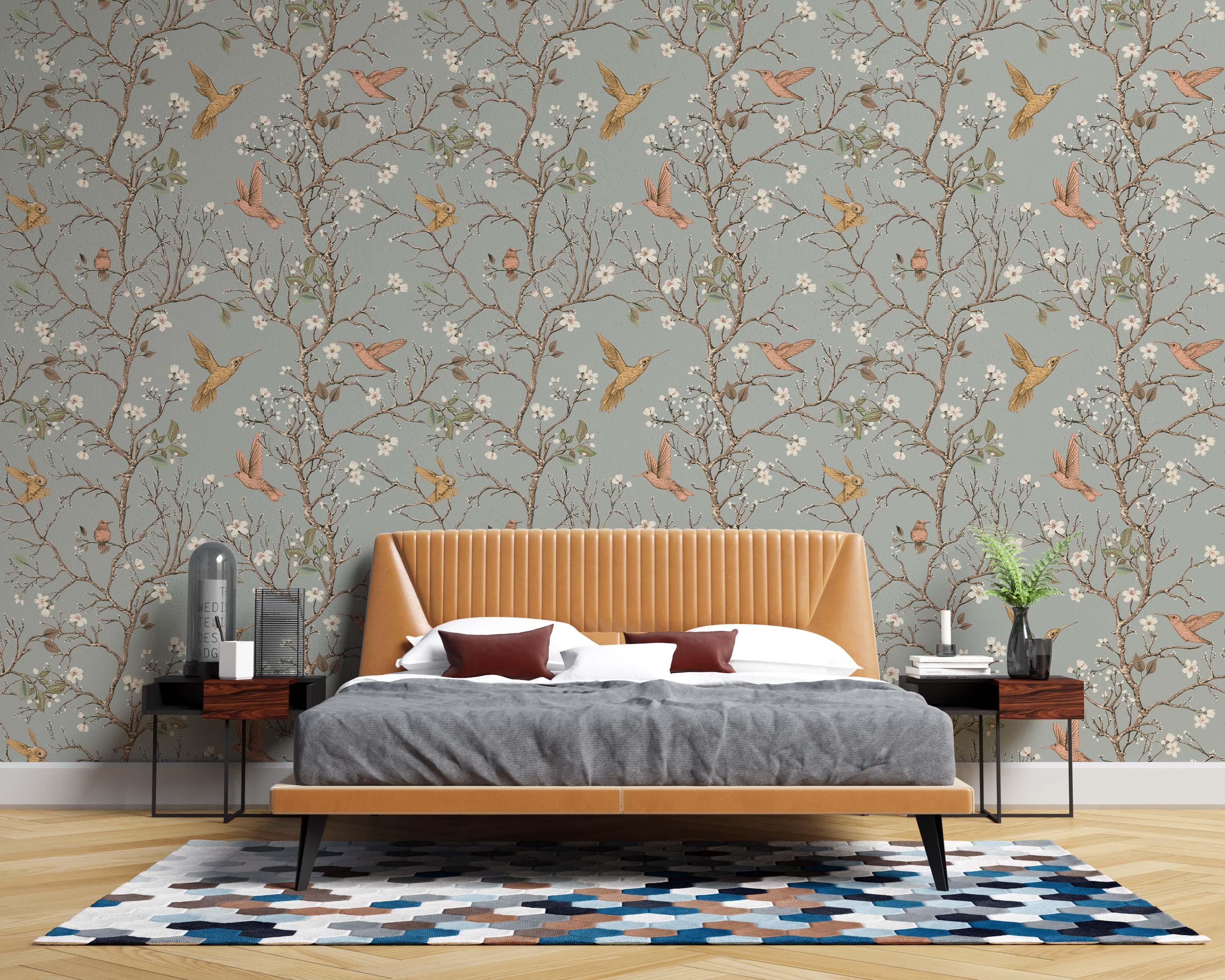 Wallpaper with a pattern of gold and pink hummingbirds flying among flowering brown branches on a dusty blue-gray background.