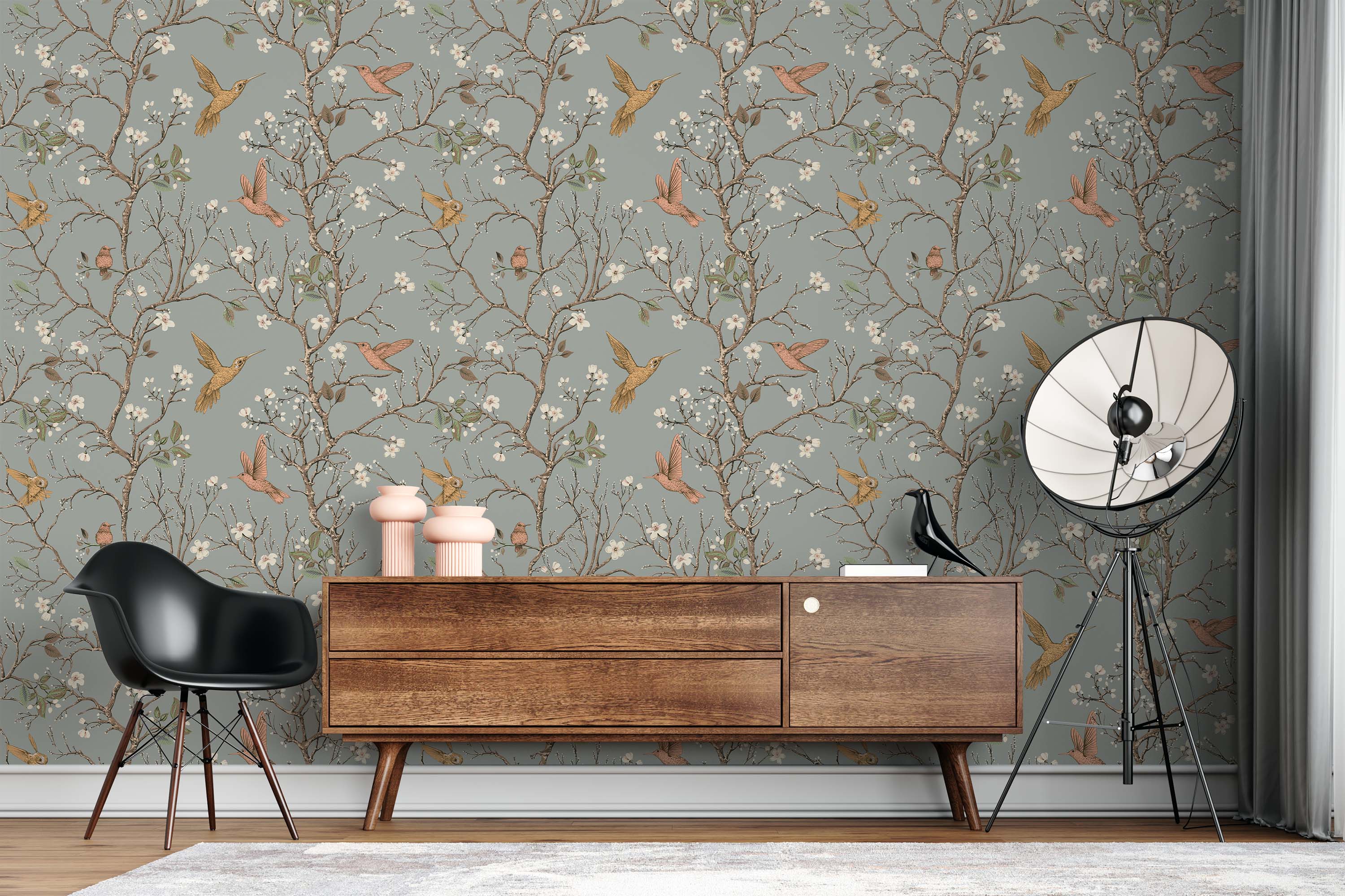 A traditional wallpaper with gold and pink hummingbirds flying among blossoming brown branches on a muted gray-blue background.