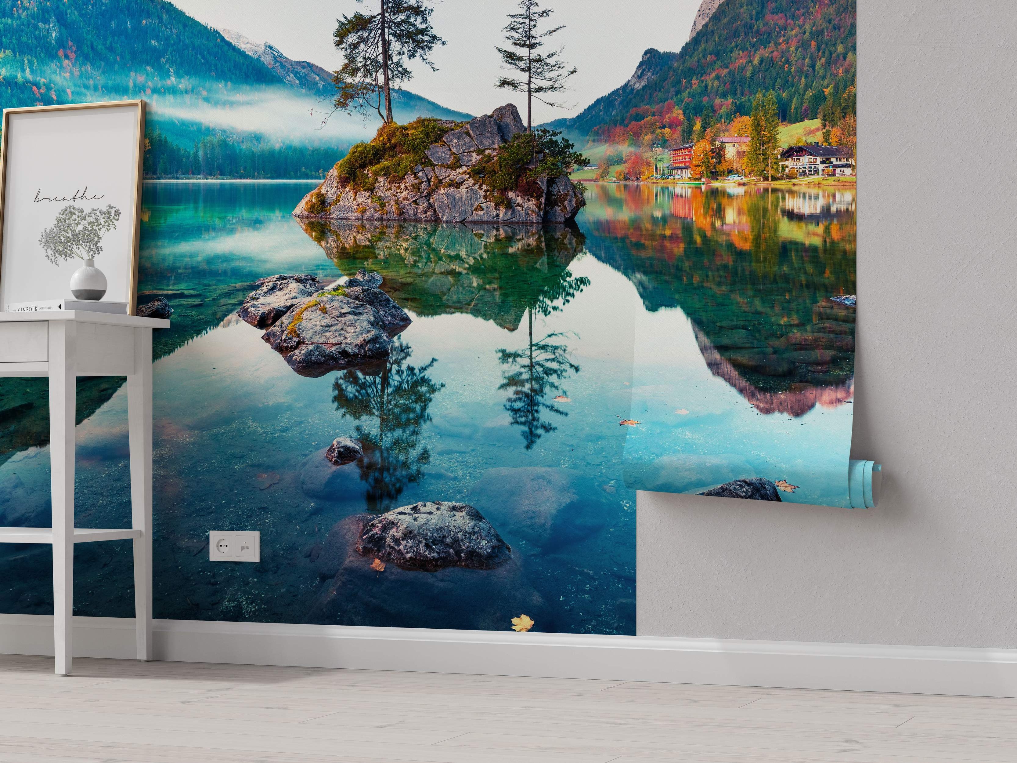 Mural of a serene alpine lake reflecting autumn-colored trees, misty mountains, and lakeside buildings in blues and greens.