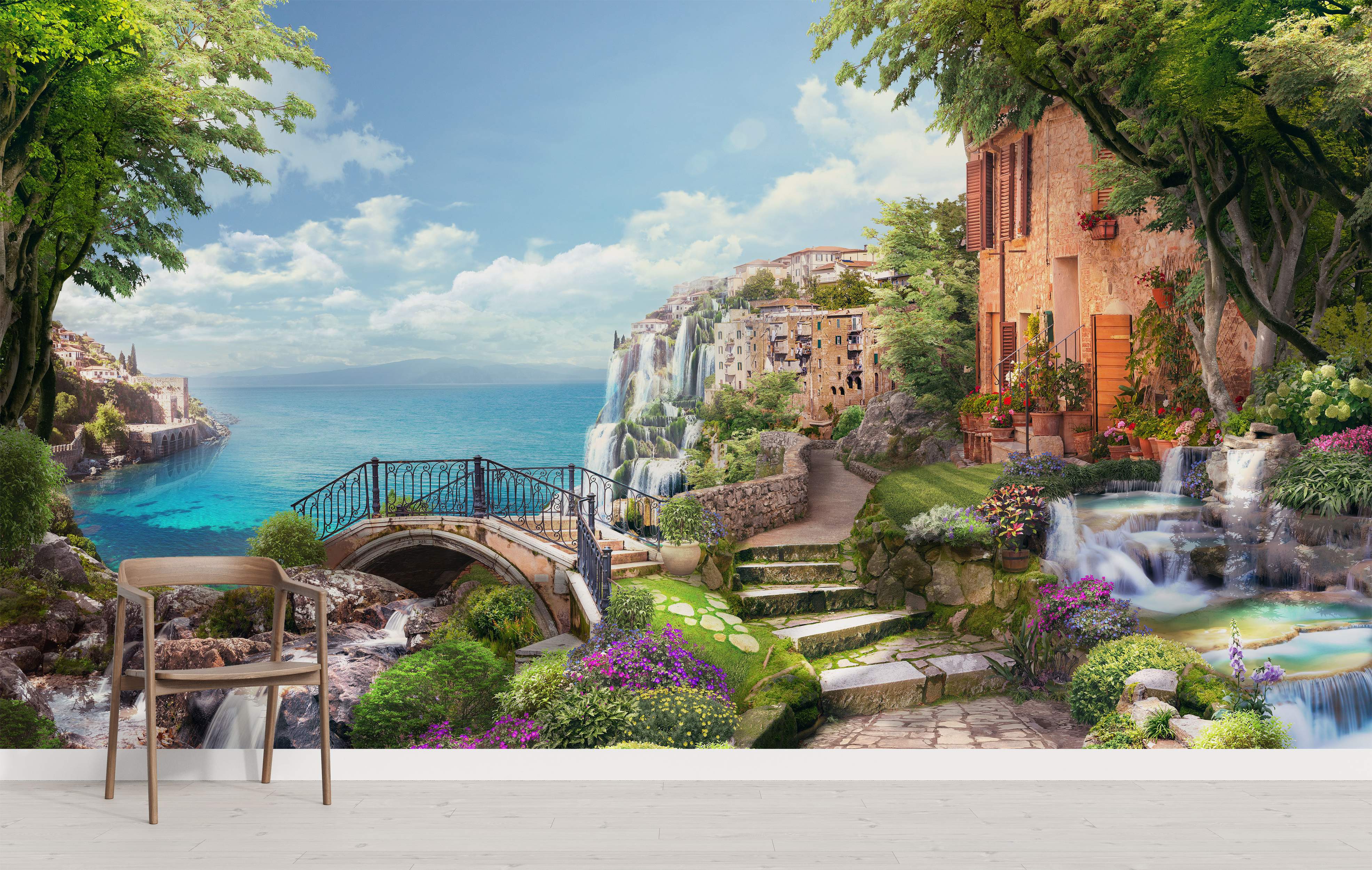 Scenic mural depicting a coastal town with waterfalls, lush greenery, stone paths, and a bright blue sea under a partly cloudy sky.