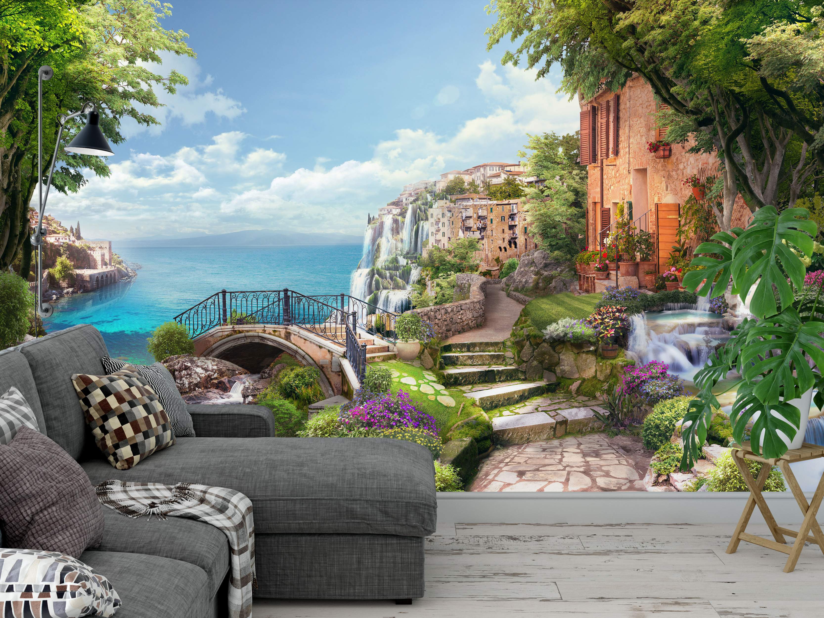 Vibrant mural depicting a coastal town scene with a stone house, waterfalls cascading into a bright blue sea, lush trees, and a stone bridge.