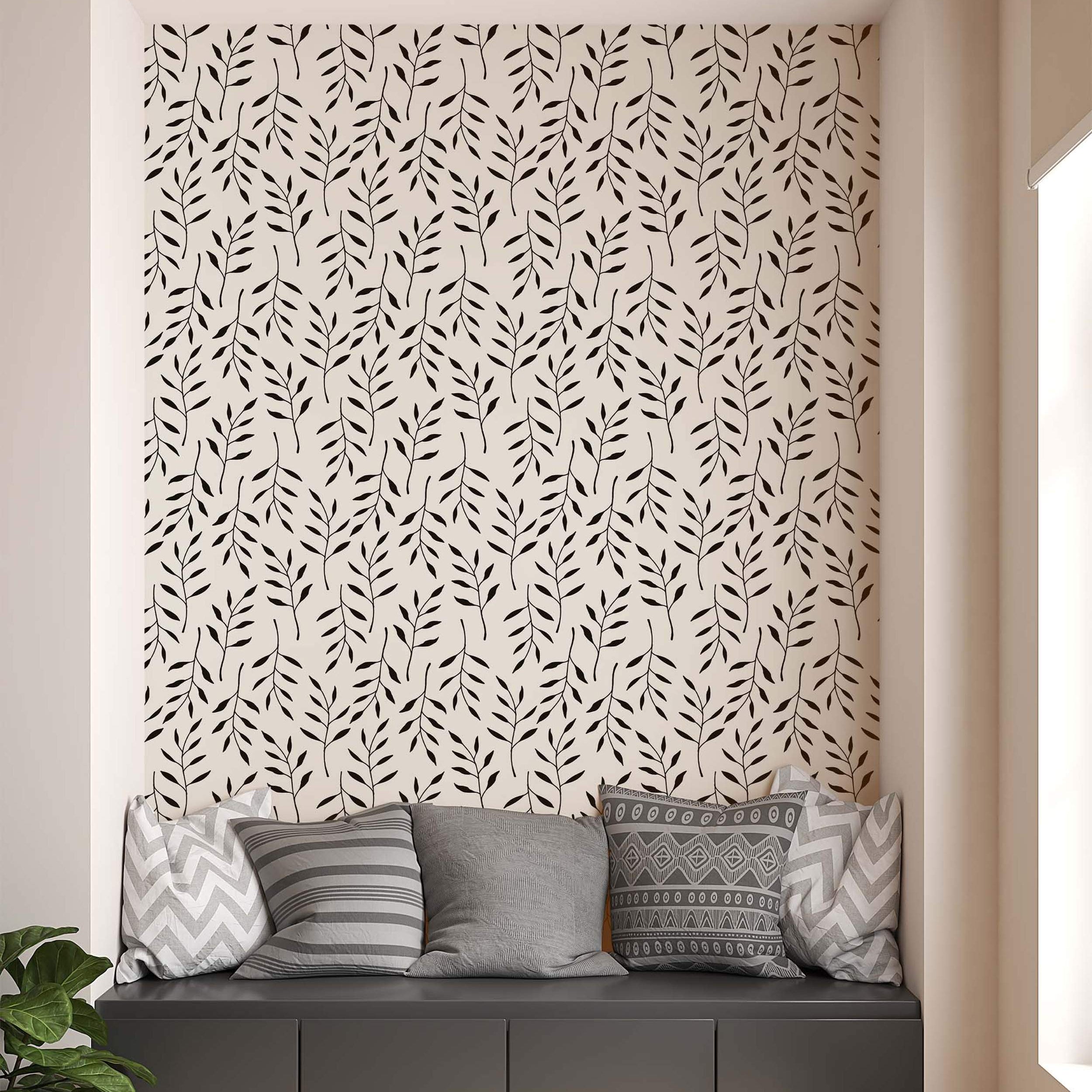 Wallpaper featuring a repeating pattern of simple black leaf branches scattered across a cream background.