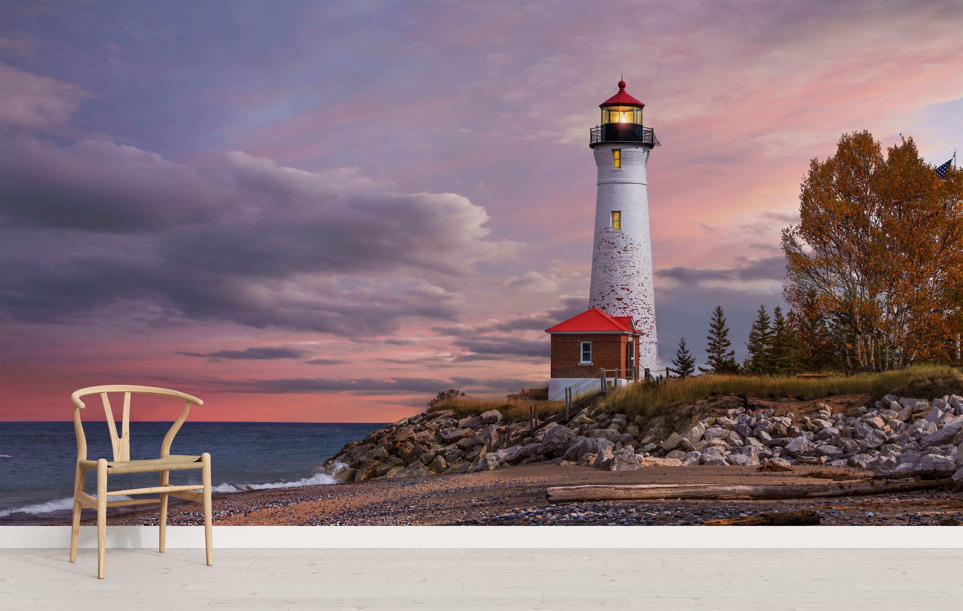Mural featuring a white lighthouse on a rocky coast beside the ocean, beneath a vibrant pink and purple sunset sky.