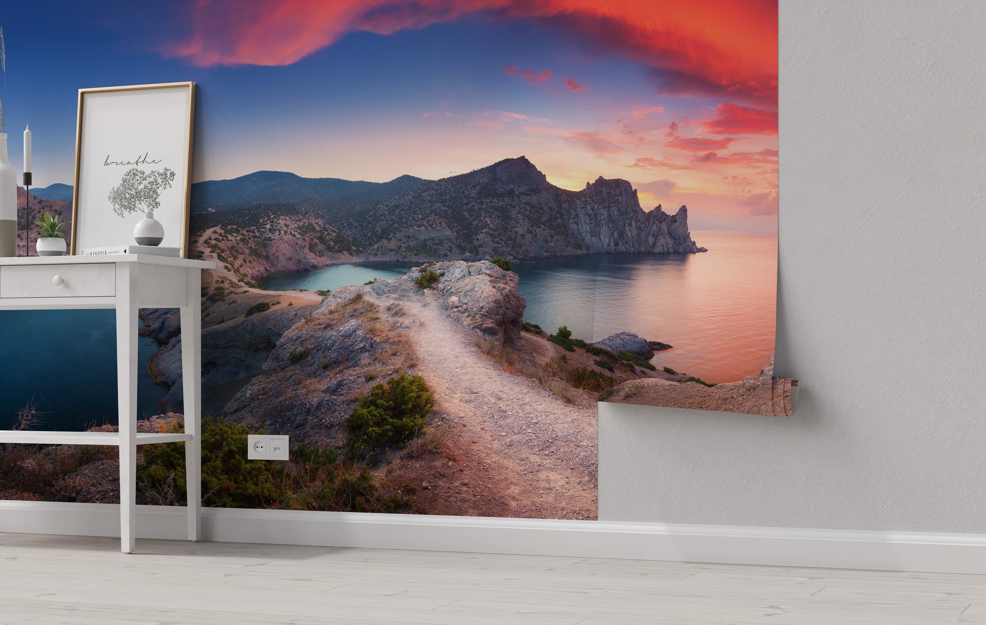 Mural depicting a dramatic coastal mountain landscape at sunset, with a path winding along a cliff overlooking the sea.