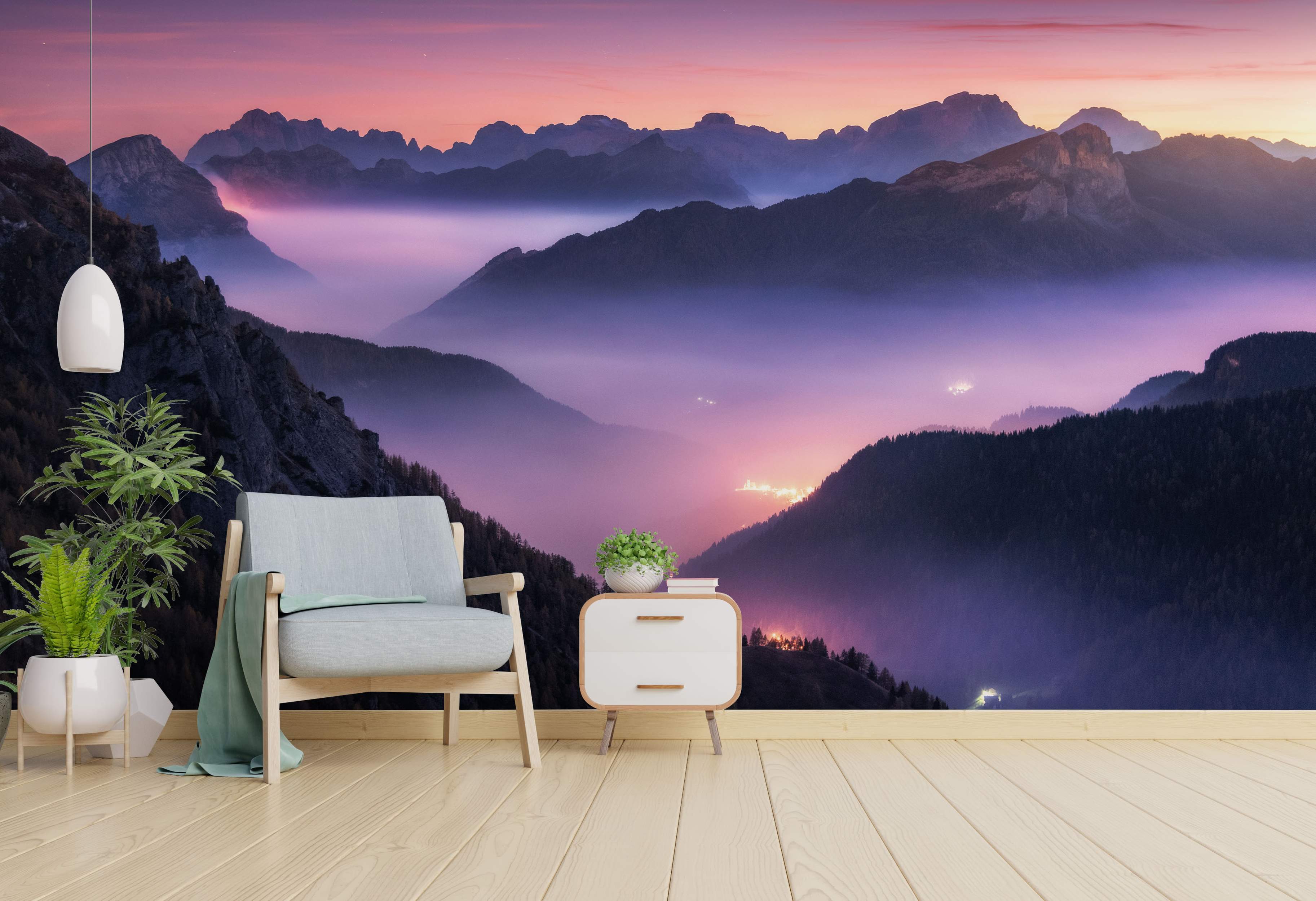 Scenic mountain mural showing layered peaks fading into foggy valleys under a pink and purple twilight sky, with glowing lights below.