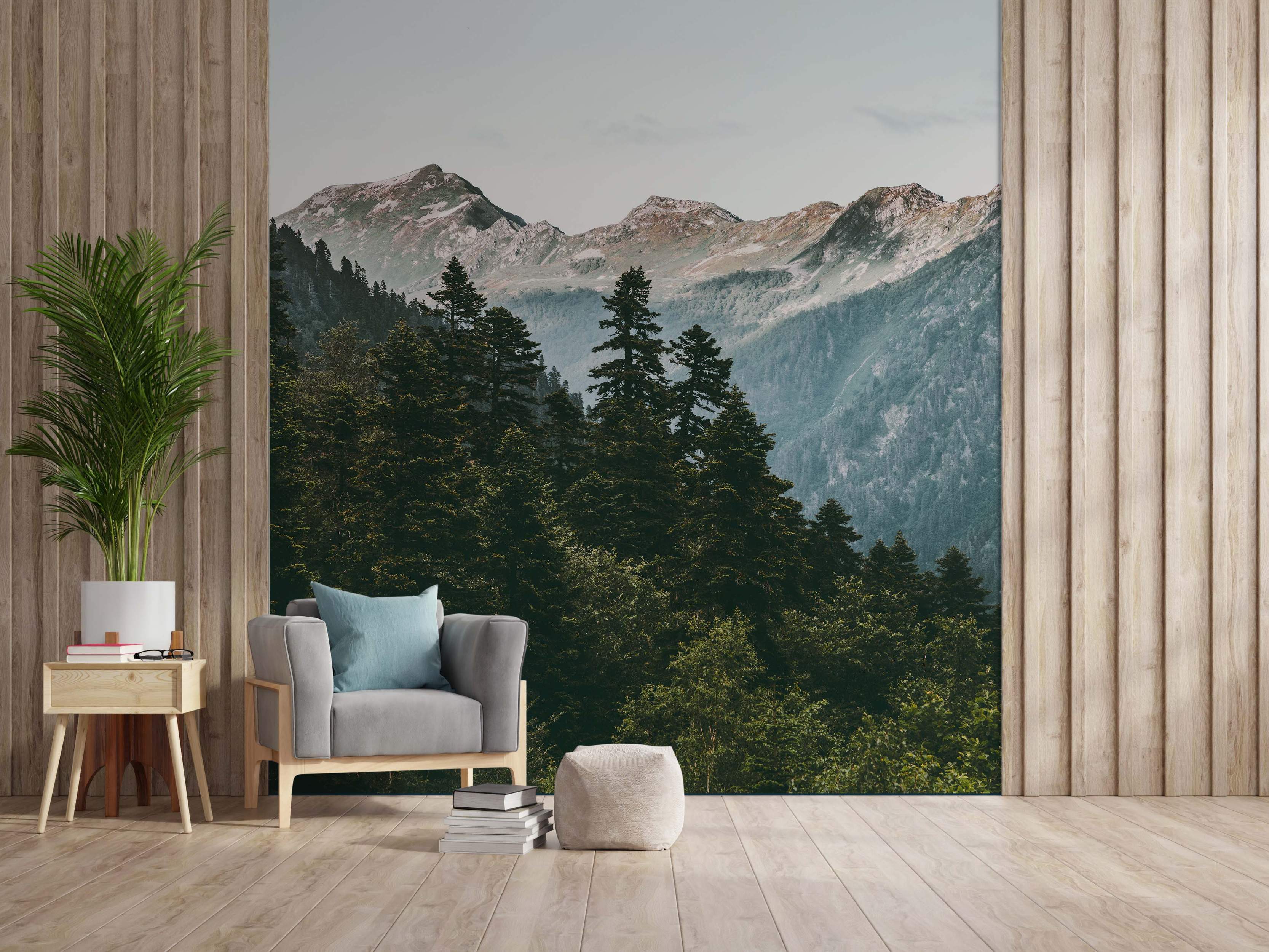 Realistic mountain mural featuring snow-capped peaks above a lush green pine forest under a pale sky.
