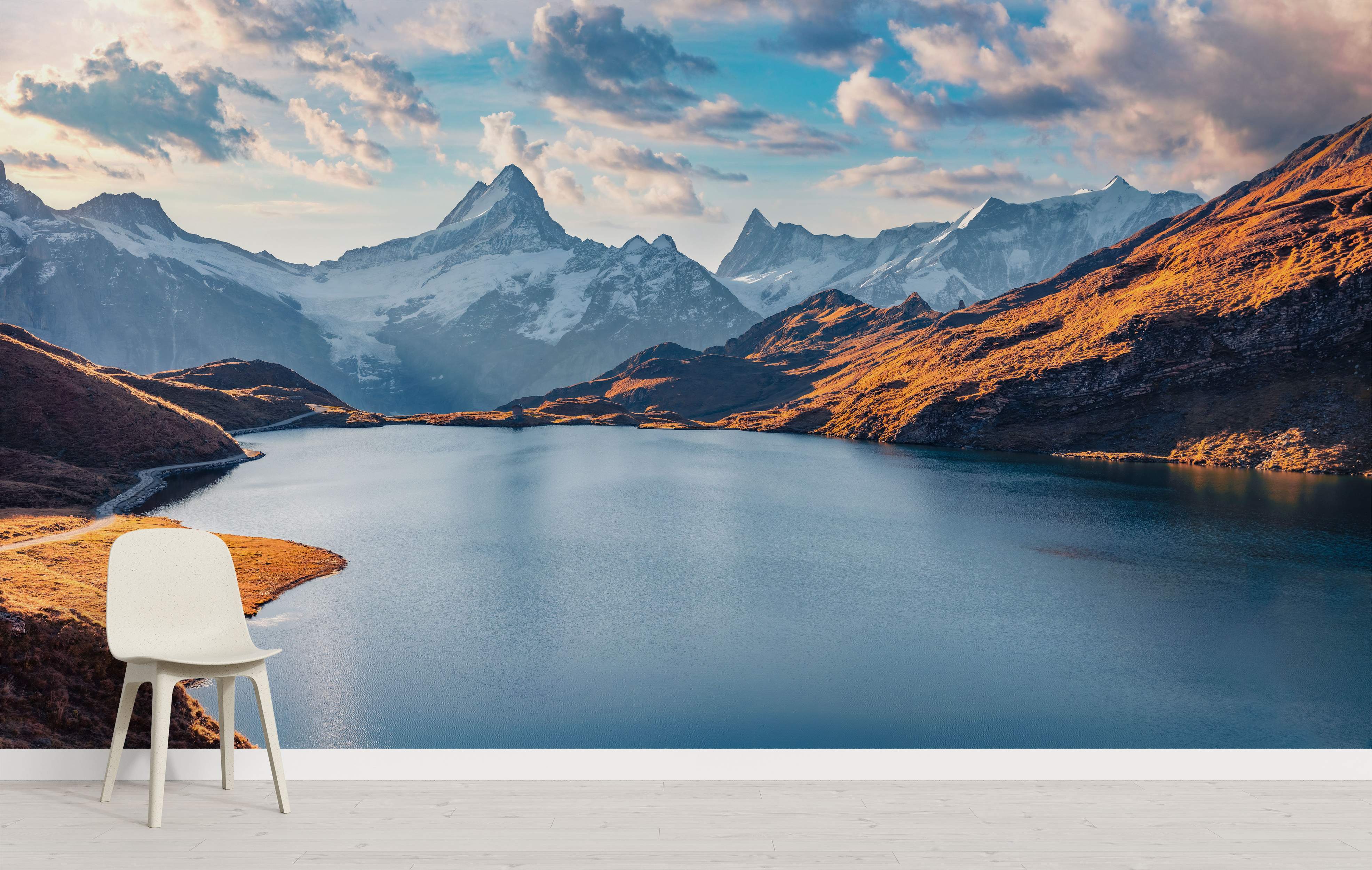 Mural depicting majestic snow-capped mountains towering over a calm blue lake, with sunlit golden slopes under a cloudy sky.