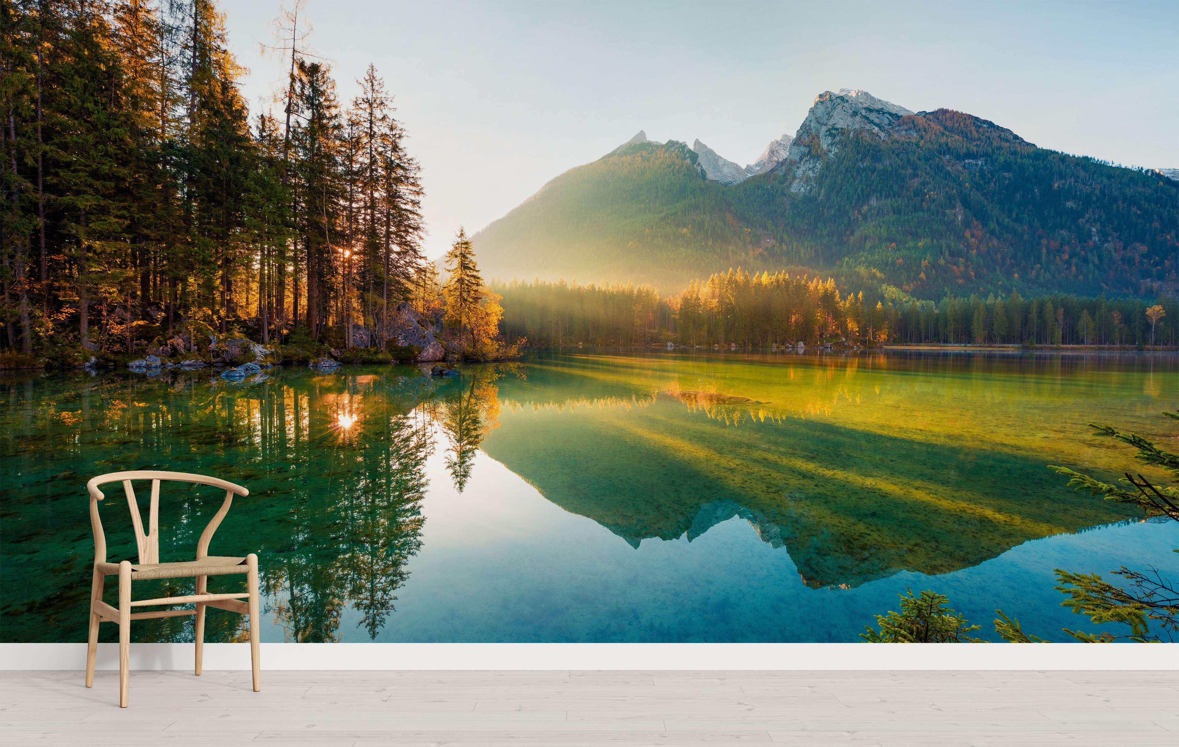 Mural depicting a serene mountain lake reflecting a pine forest and peaks bathed in warm sunrise light.