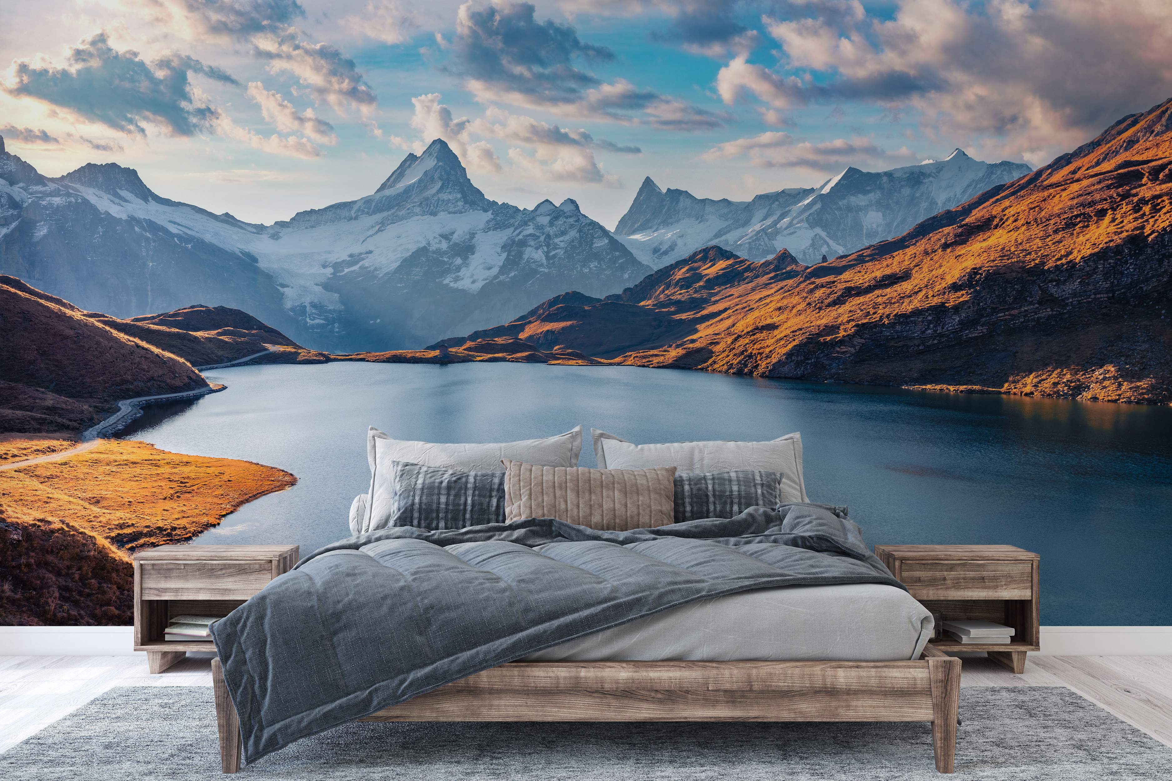 Scenic mountain landscape mural with a blue lake, sunlit orange hills, snow-capped peaks, and a cloudy blue sky.