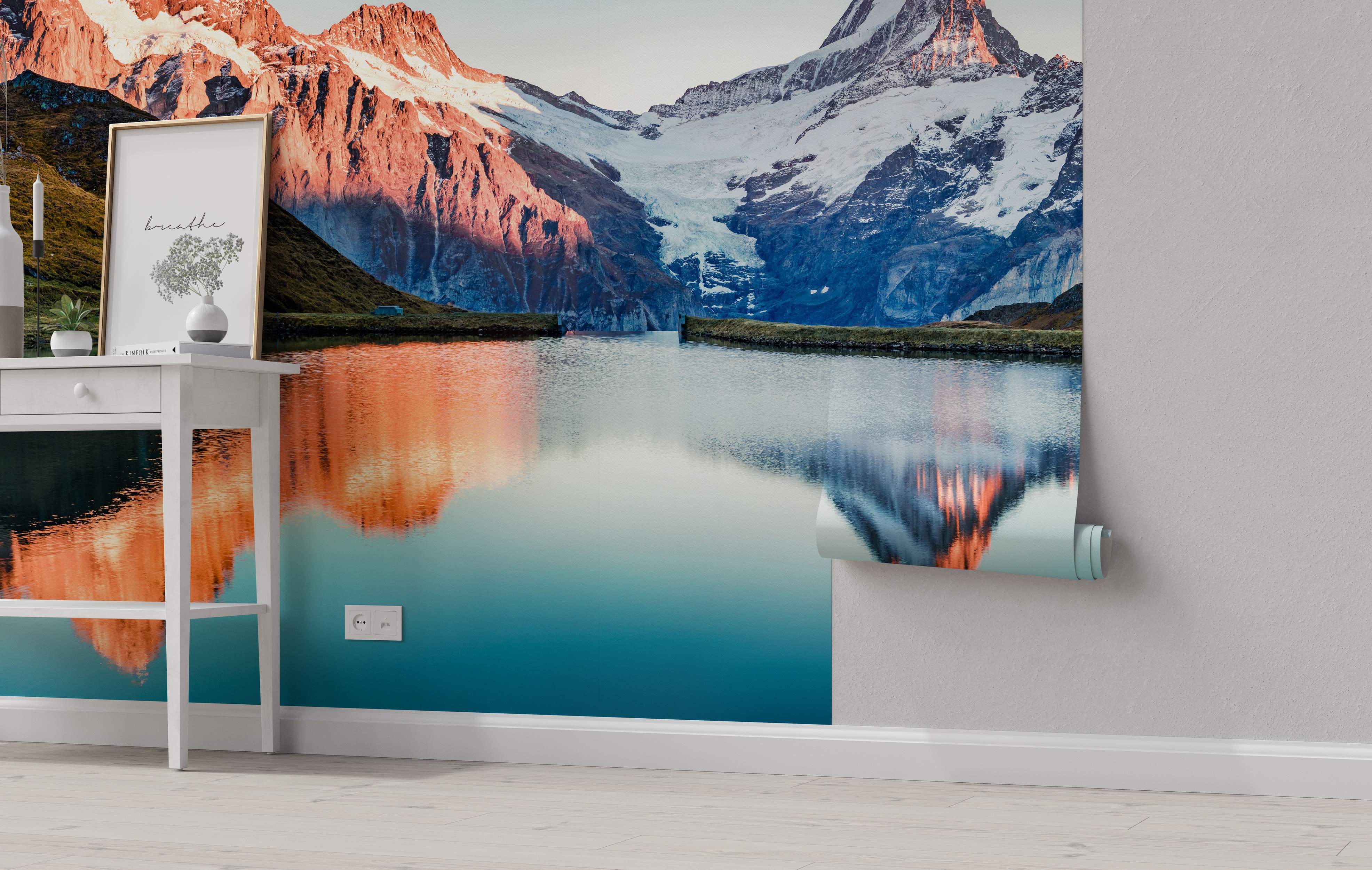 Scenic mural depicting sunlit red mountains and shadowed blue peaks reflected in a tranquil lake with snowy tops.