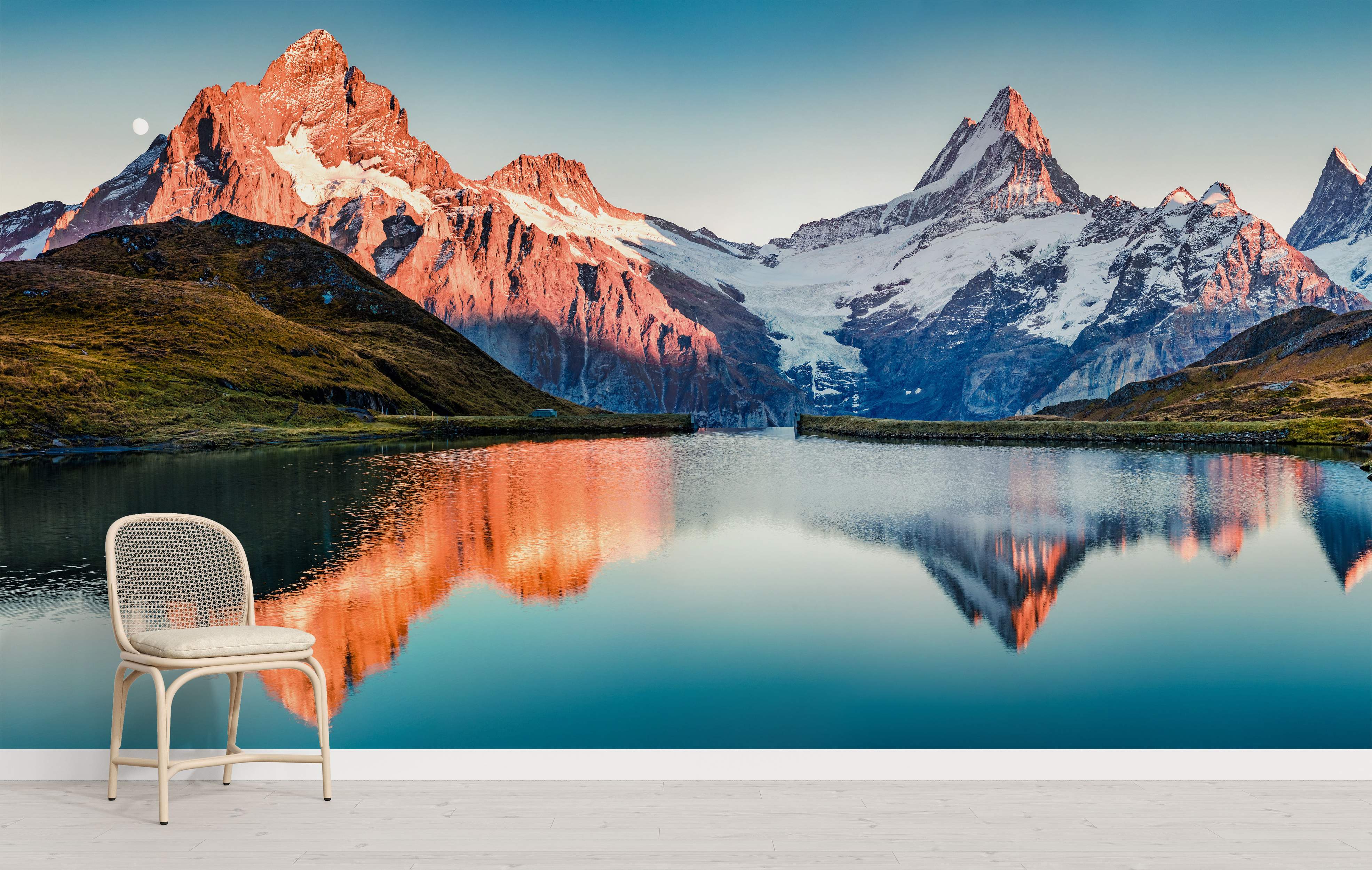 Scenic mountain mural with snow-capped peaks glowing orange at sunrise, perfectly reflected in a calm blue lake below.