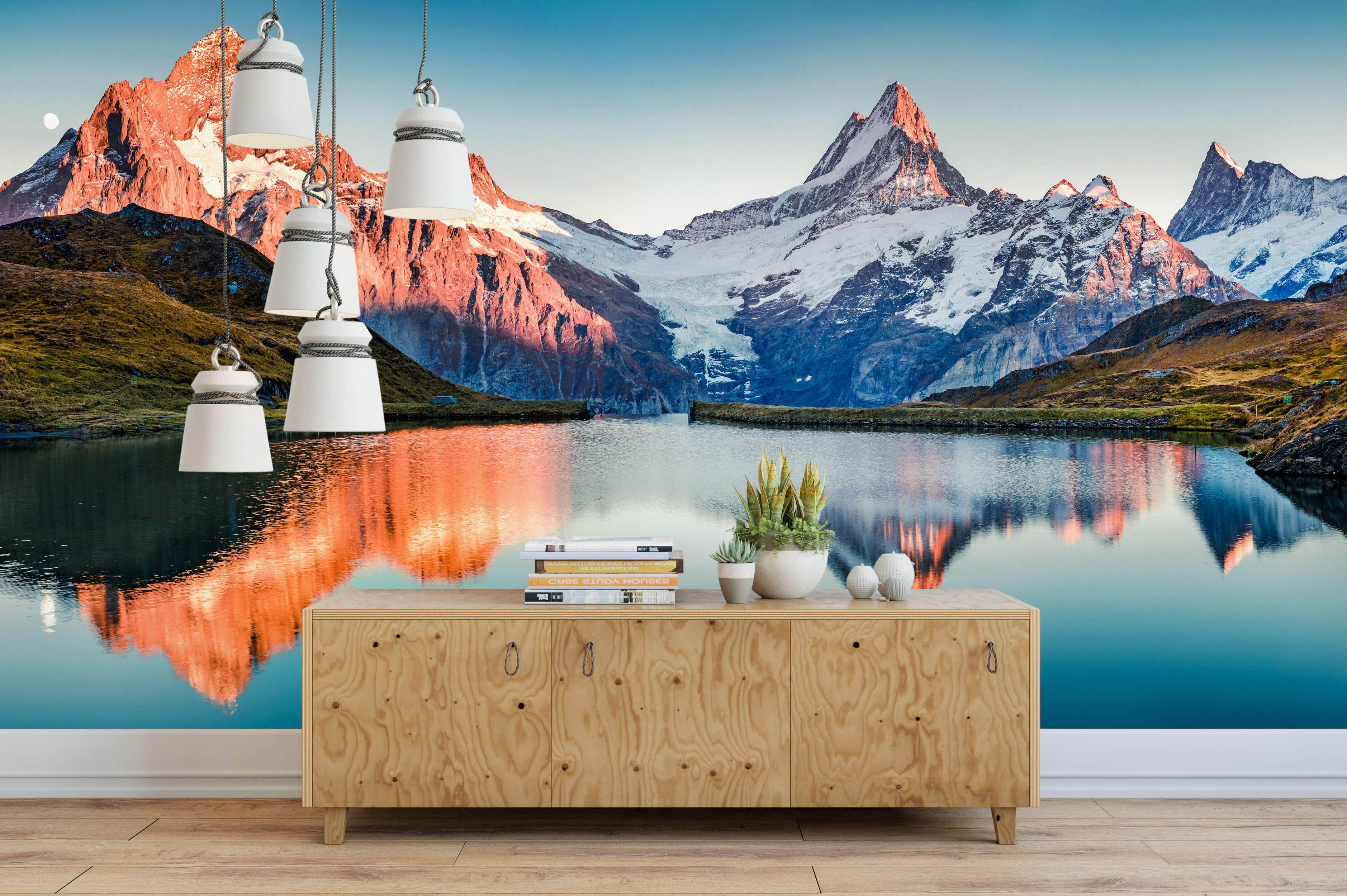 Mural depicting a majestic mountain range with snow-capped peaks glowing orange at sunset, reflected in a calm blue lake.