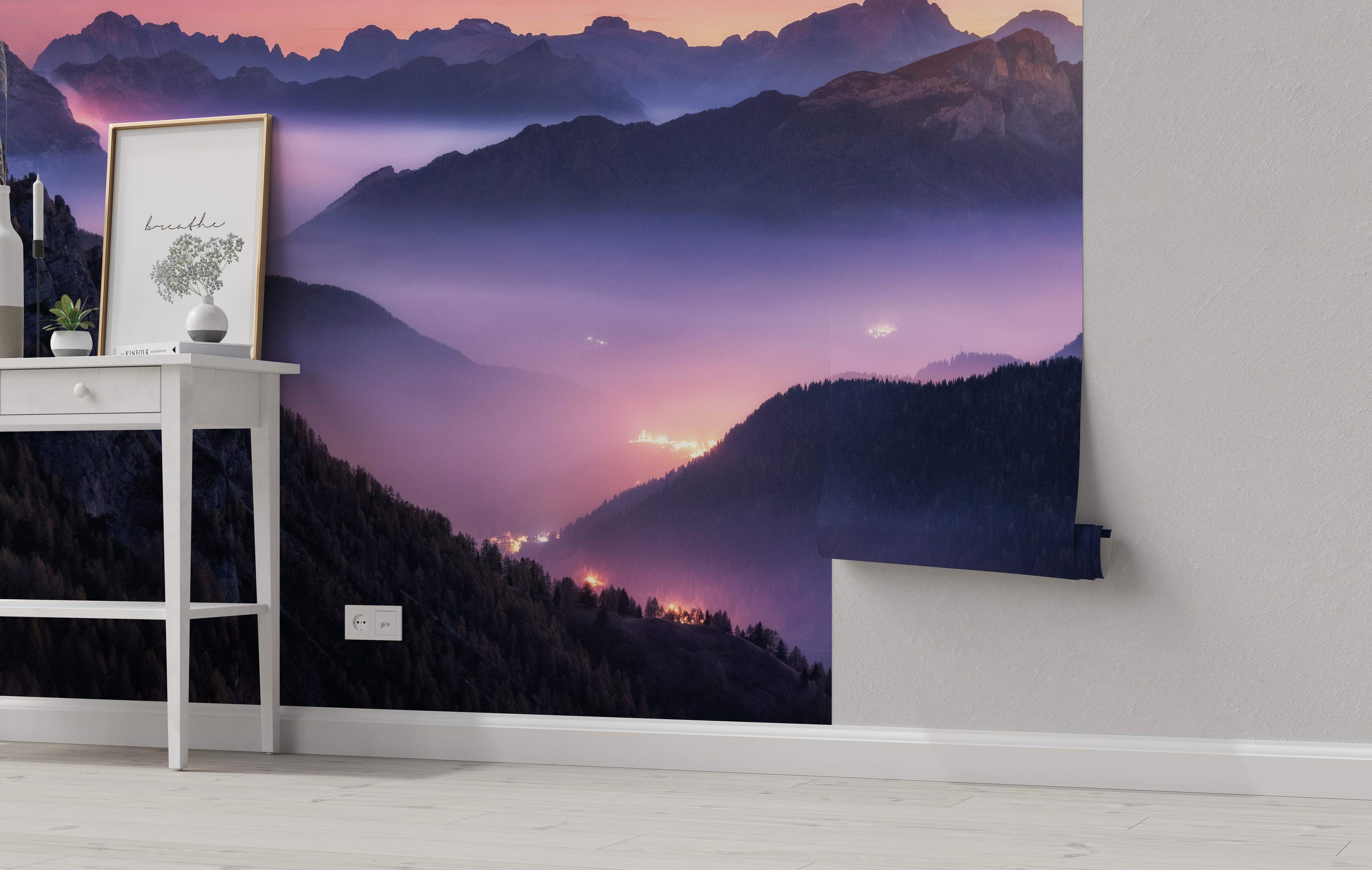 Misty mountain landscape mural in shades of purple and pink twilight, showing valley lights below.