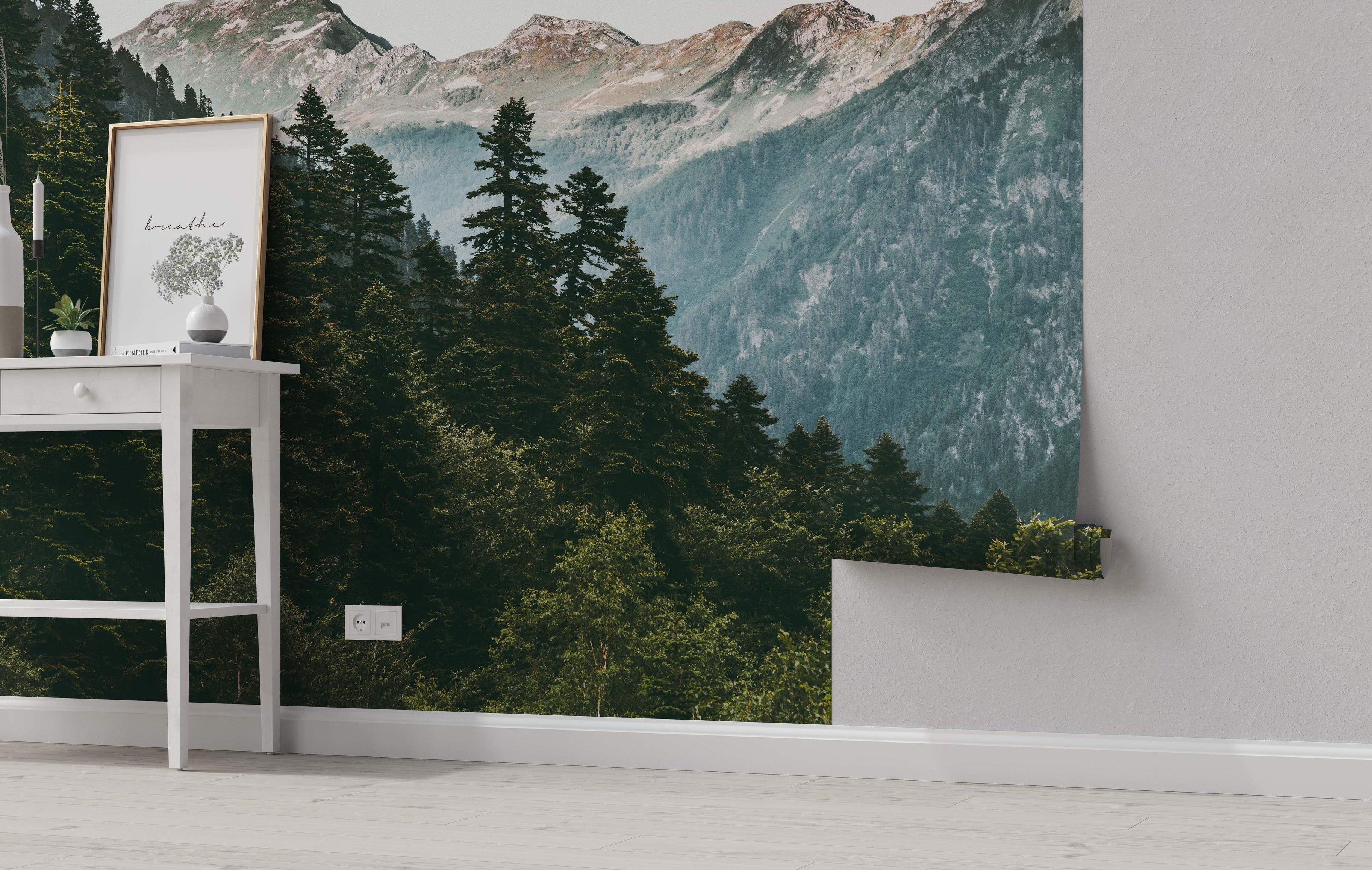 Realistic mountain landscape mural featuring a dense green evergreen forest below hazy gray and brown rocky peaks.