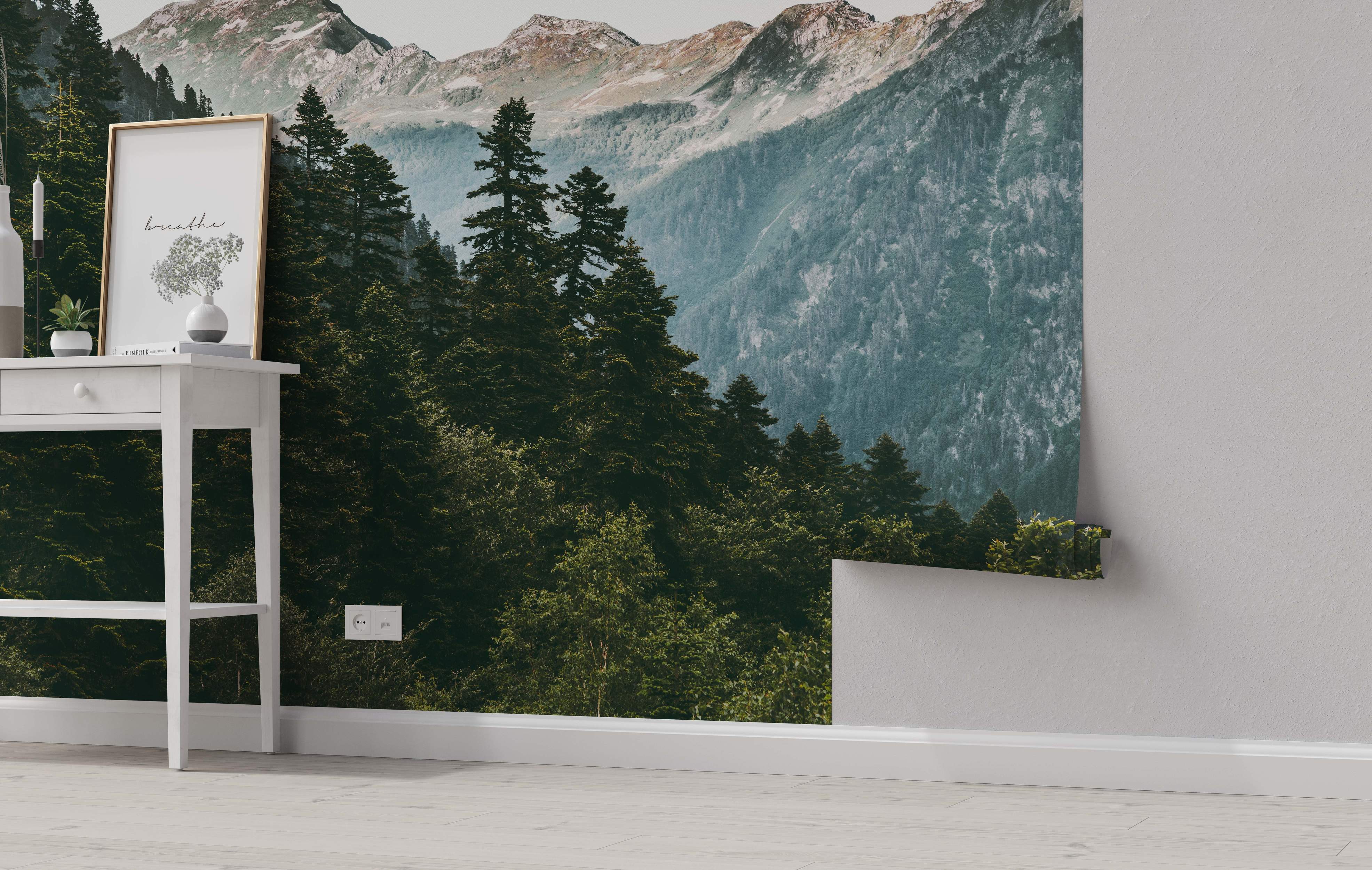 Realistic mountain landscape mural featuring a dense green evergreen forest below hazy gray and brown rocky peaks.
