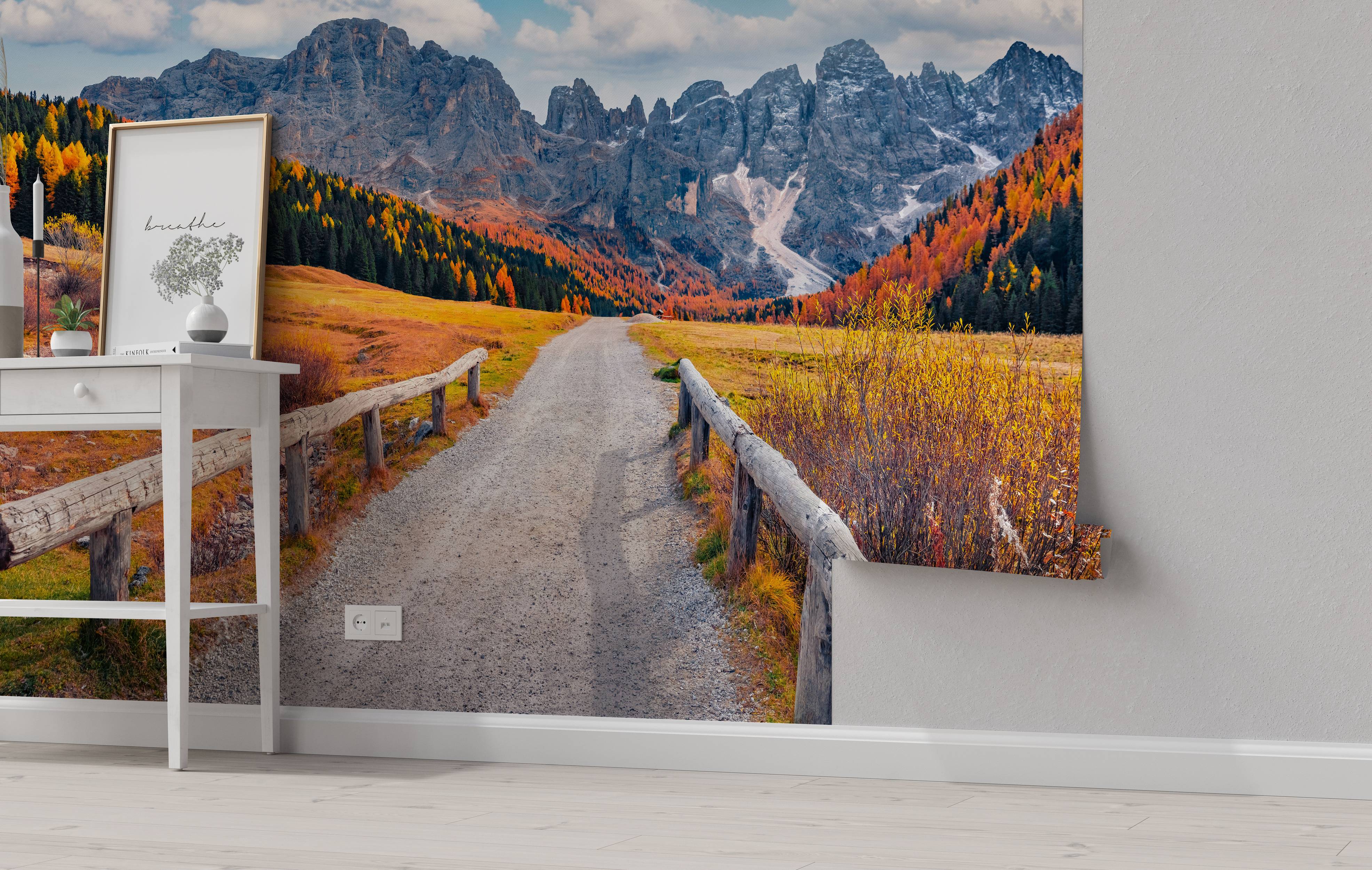 A scenic mural of a gravel road leading towards a rocky mountain range, with vibrant orange and yellow autumn trees.