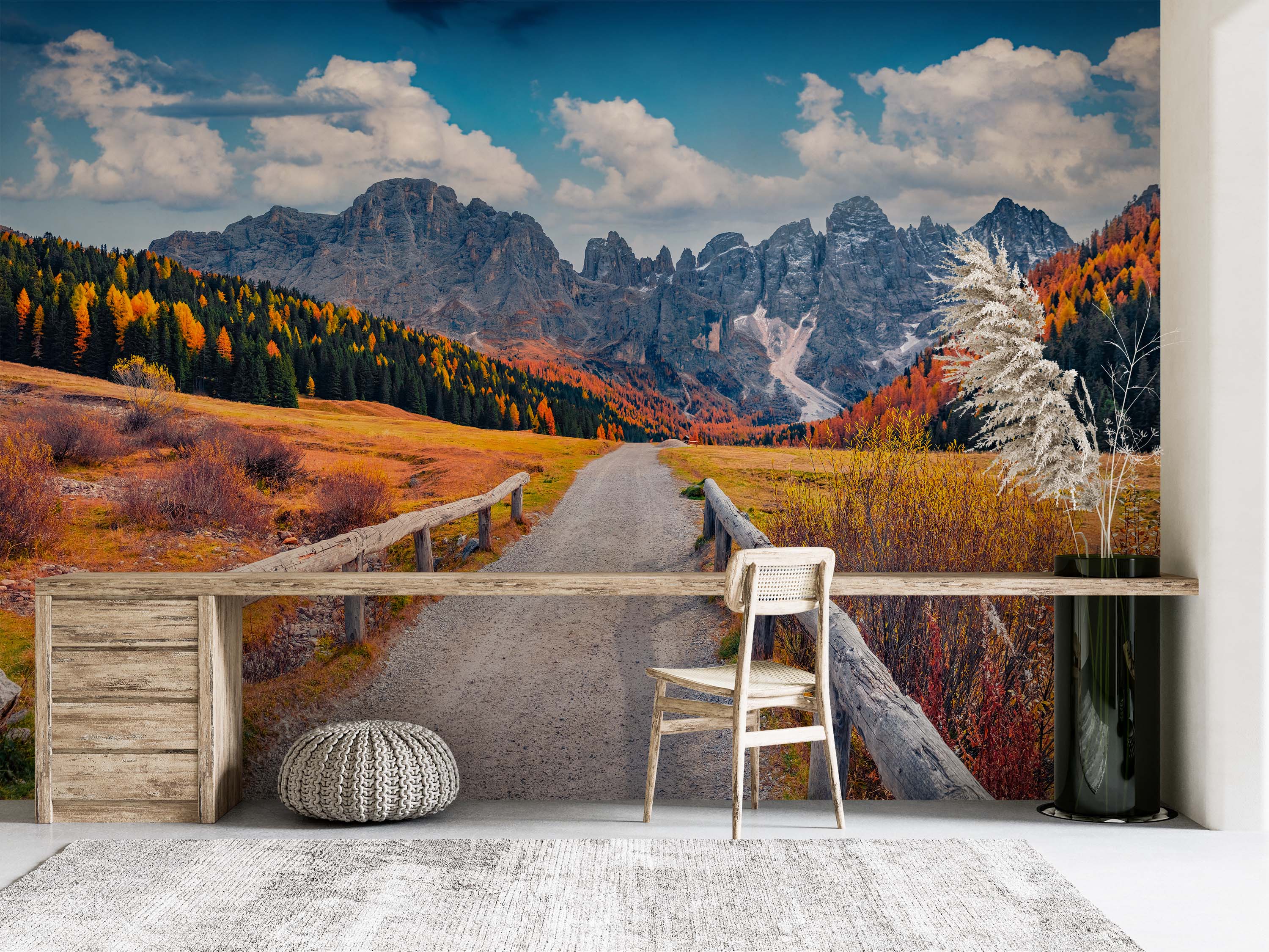 A scenic mural of a gravel road leading towards rocky mountains, surrounded by colorful orange and yellow autumn trees.