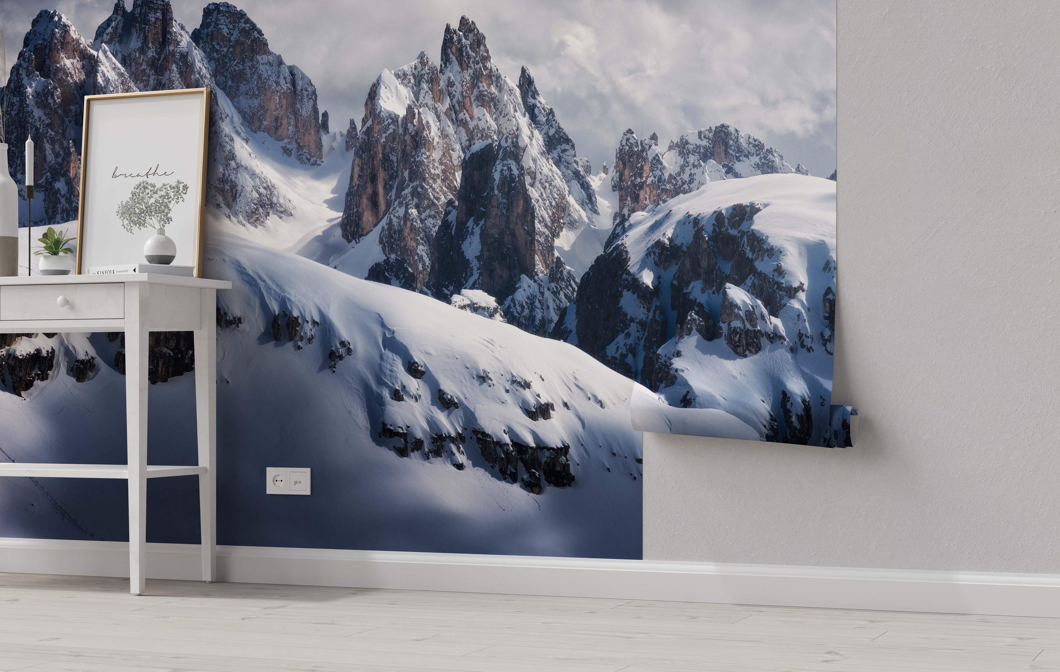 Photographic mural depicting majestic snow-covered mountain peaks with sharp, rocky ridges under a cloudy gray sky.