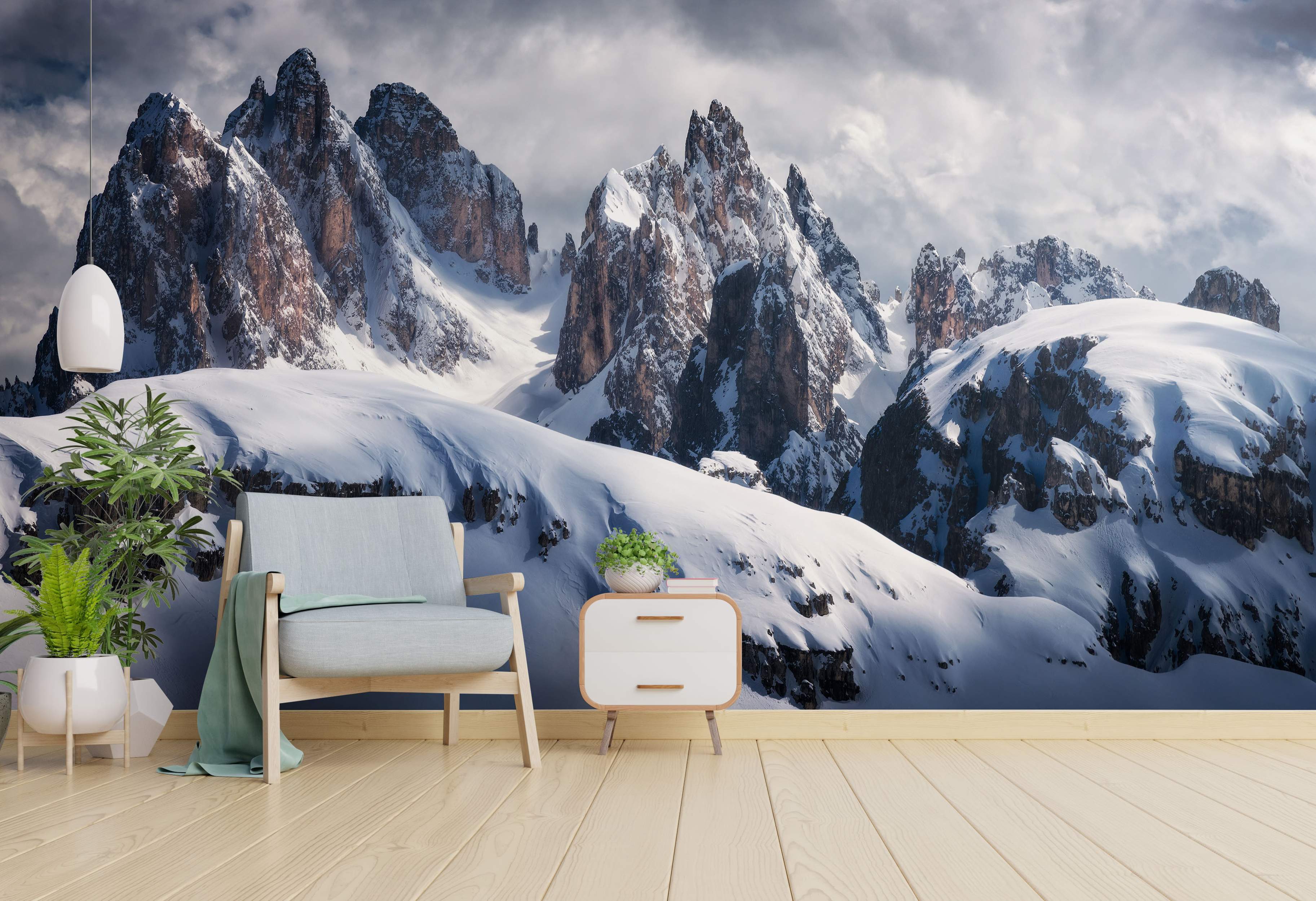 Photorealistic wall mural depicting jagged, snow-covered mountain peaks under a dramatic, cloudy gray sky.