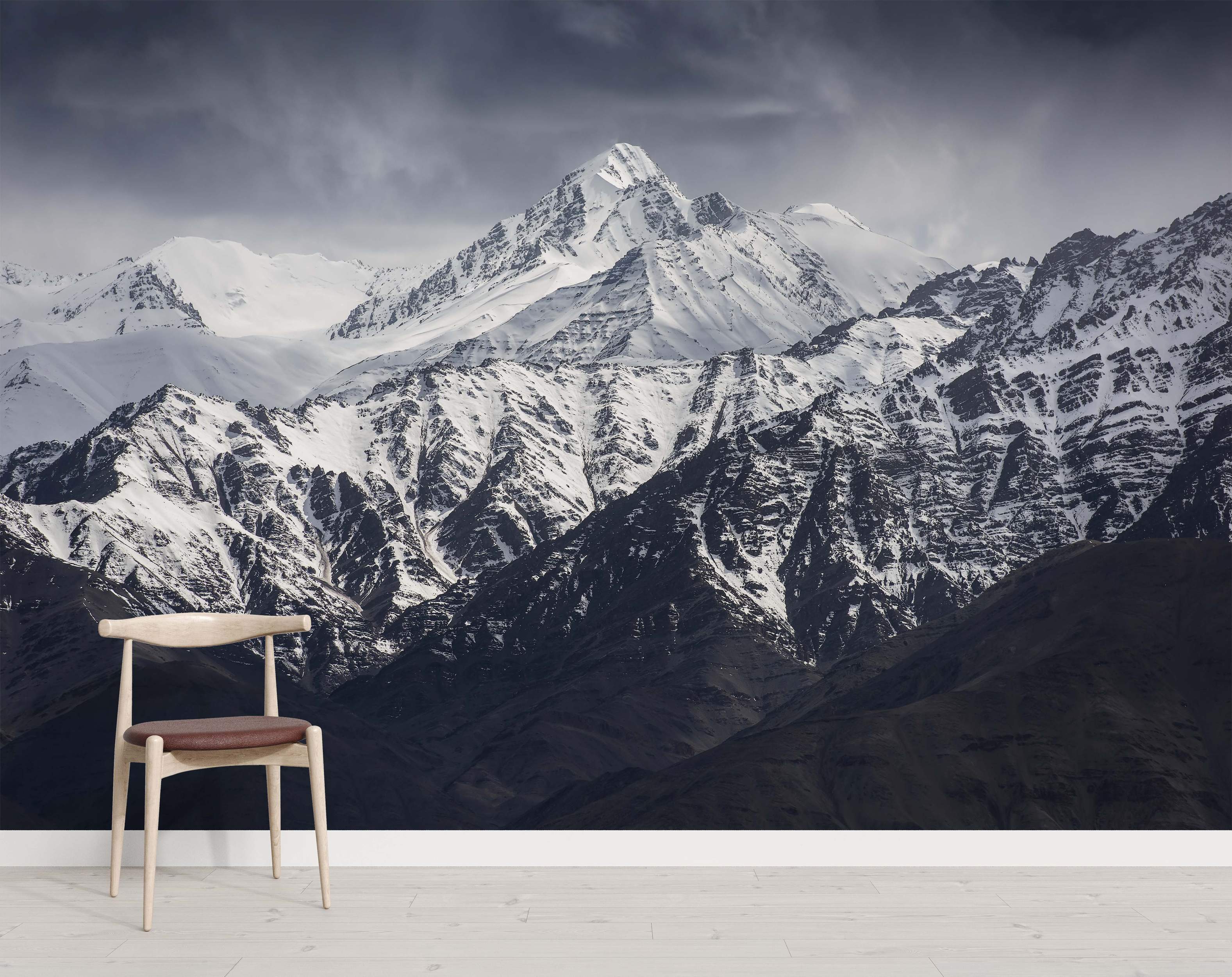 Mural of majestic snow-capped mountain peaks under a moody, dark gray sky, with strong white and dark rock contrasts.