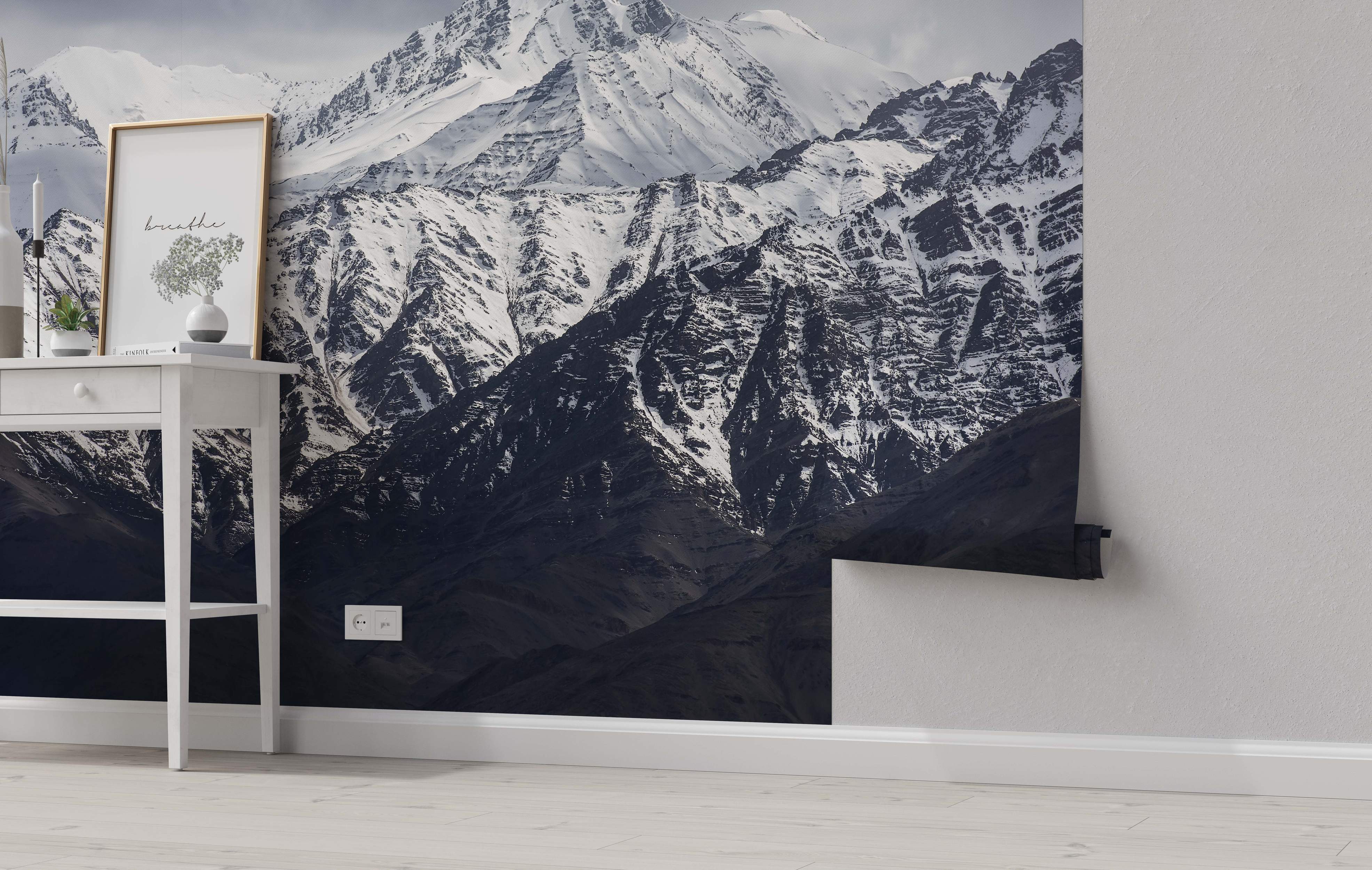 Photographic mural featuring dramatic snow-covered mountains with dark rocky faces under a cloudy gray sky.