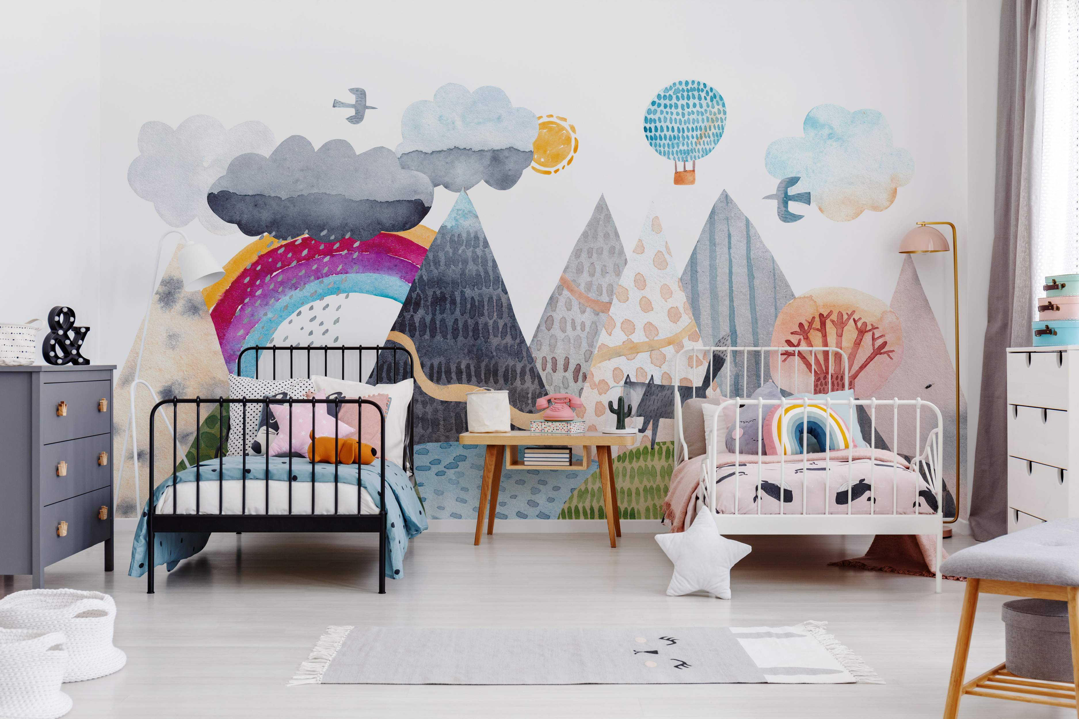 Watercolor landscape mural featuring patterned mountains, clouds, a vibrant rainbow, sun, and birds in blues, grays, and pinks.