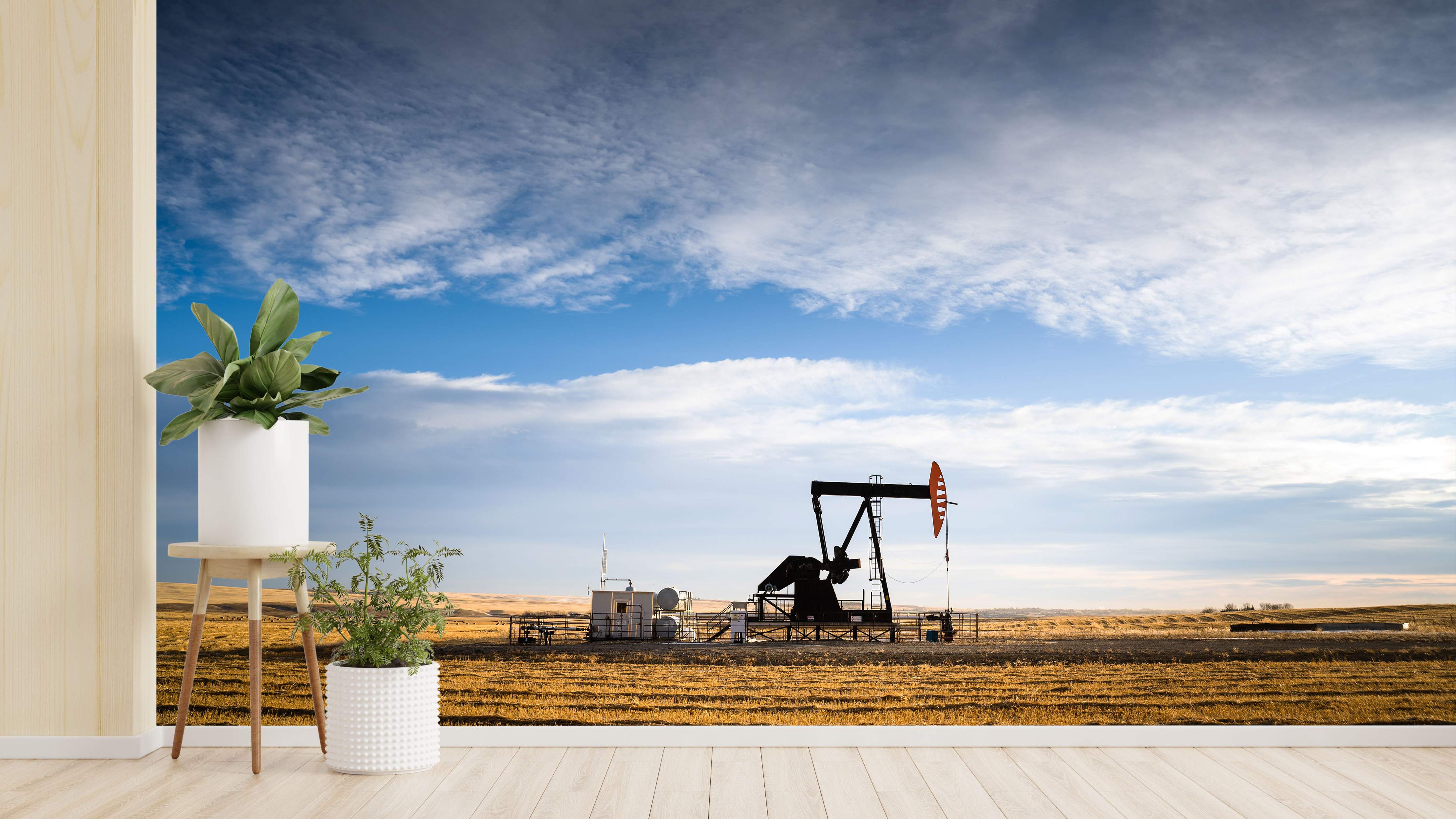 Photographic mural depicting an oil pump jack operating in a golden field under a blue sky with scattered white clouds.