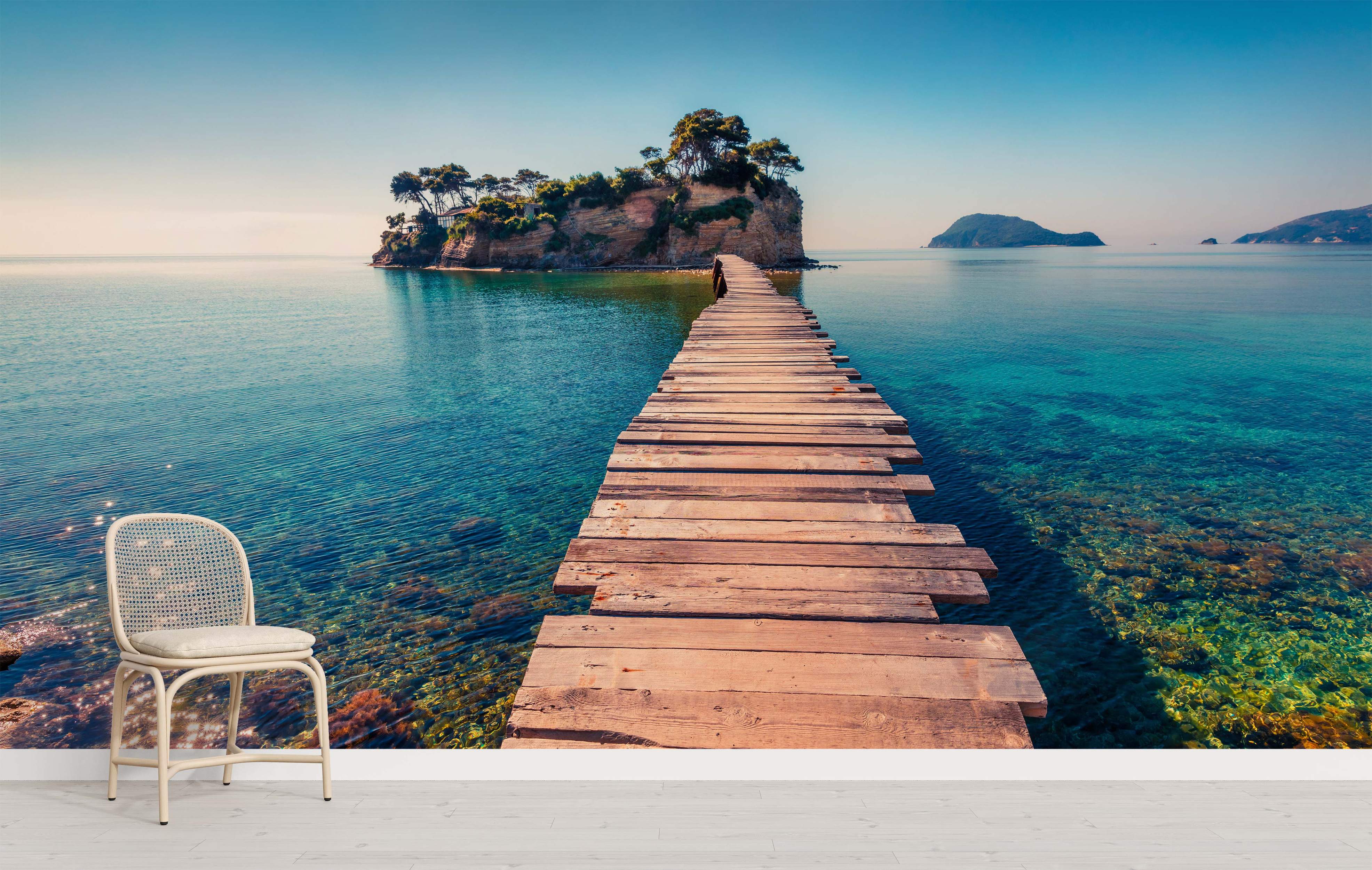 Mural depicting a wooden pier leading over clear turquoise water to a small, tree-covered rocky island under a blue sky.