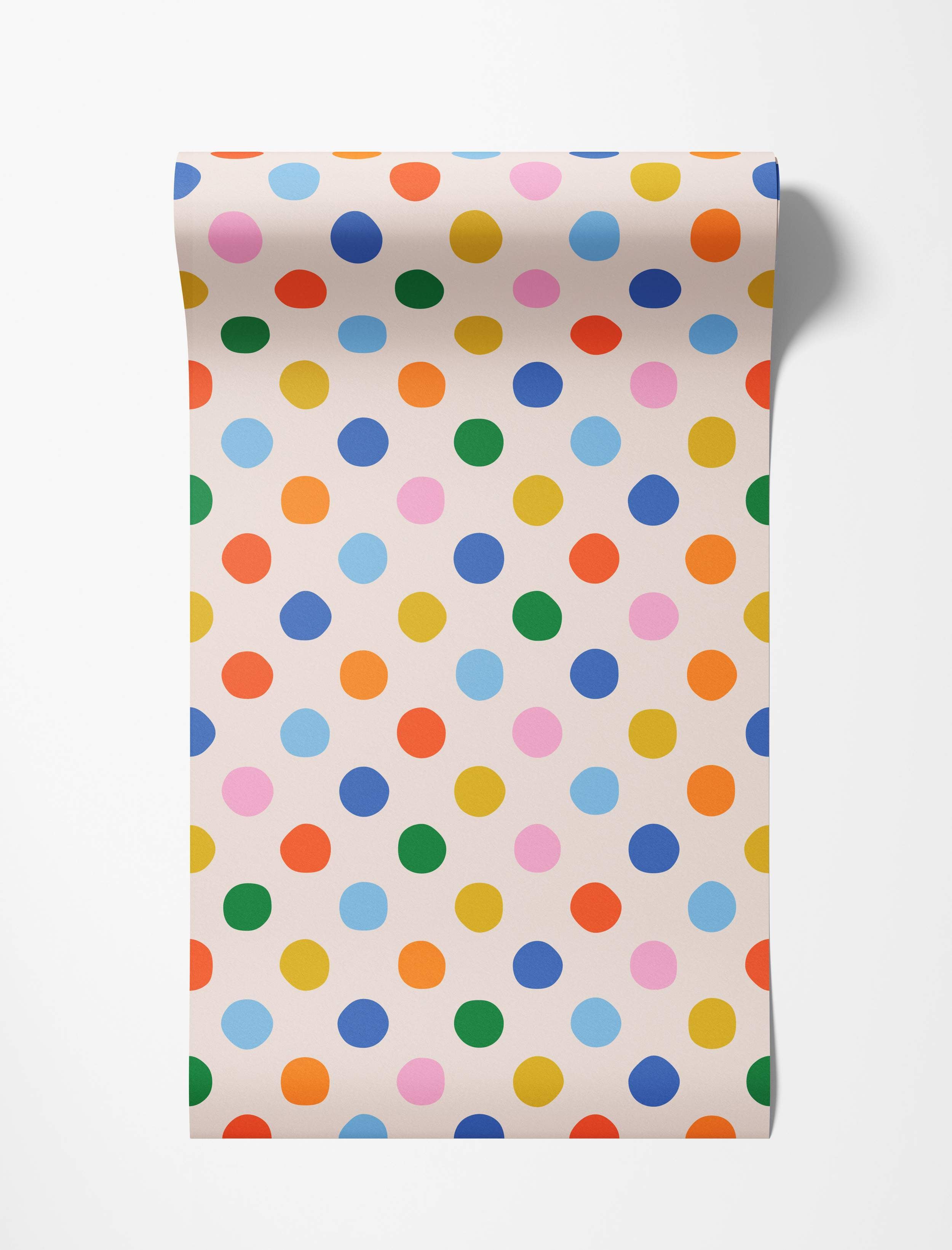 Wallpaper featuring a playful pattern of multicoloured polka dots in blue, green, yellow, orange, and pink on a light cream background.