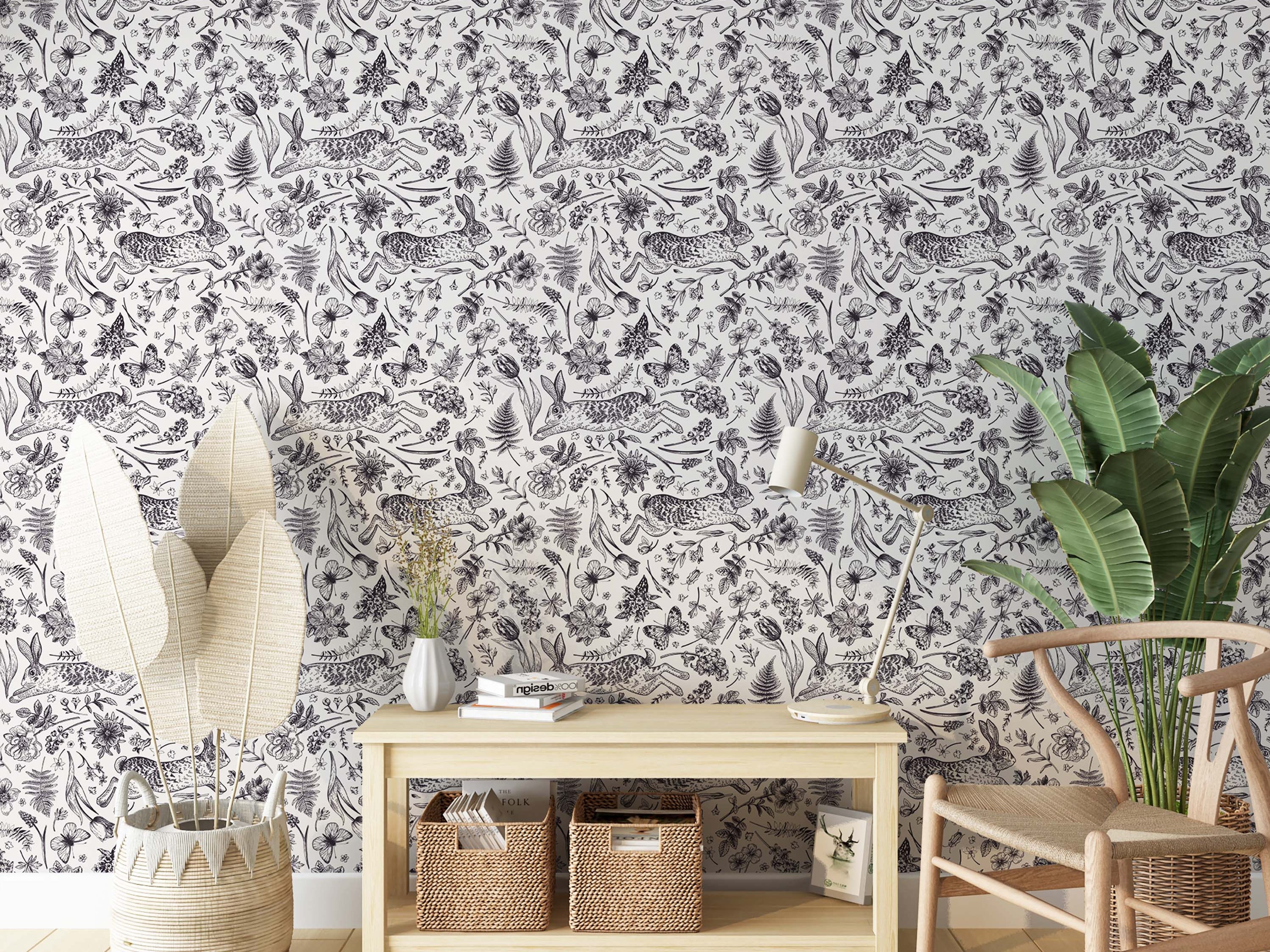 A hand-drawn toile wallpaper with a repeating pattern of leaping rabbits, butterflies, and florals in black on white.
