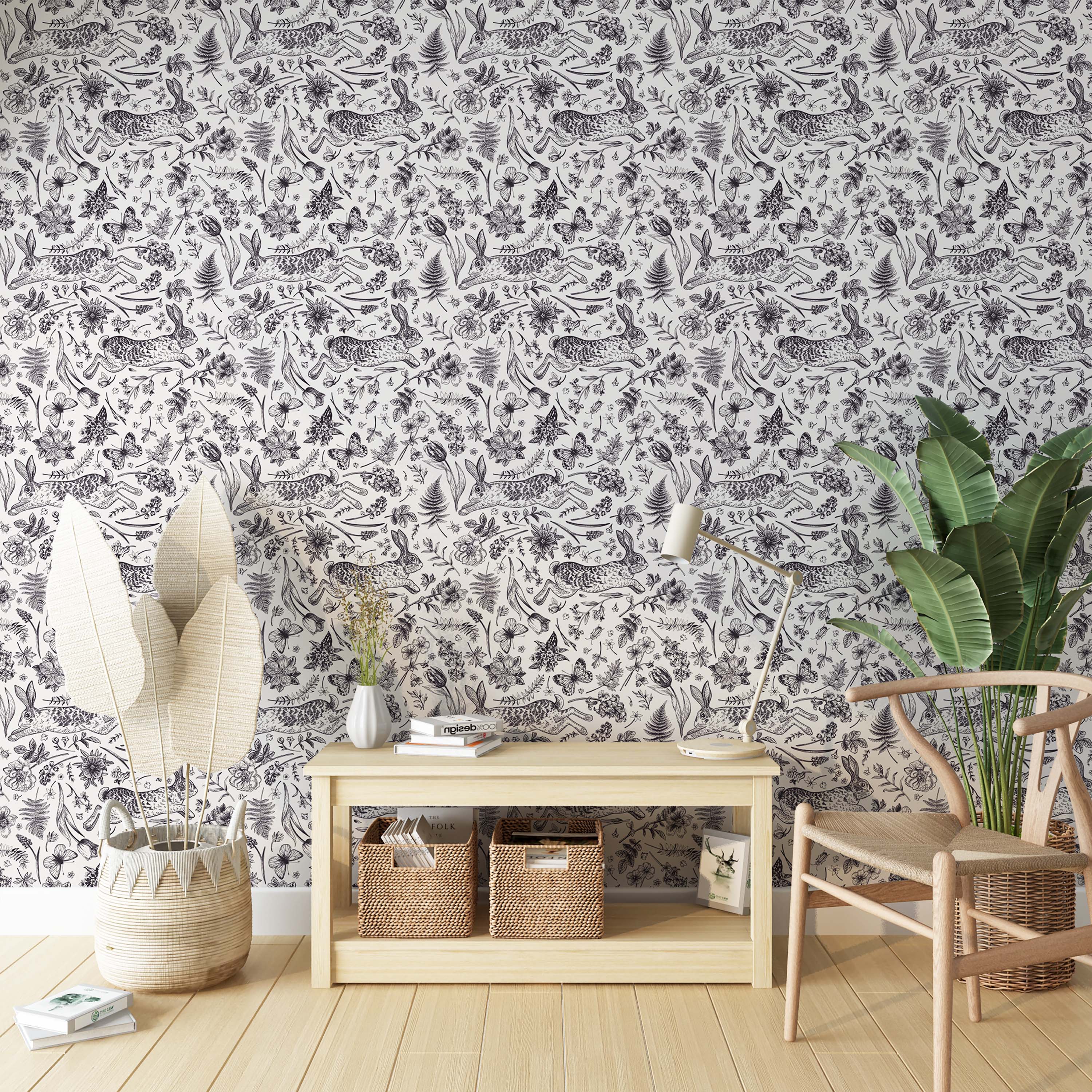 A hand-drawn toile wallpaper with a repeating pattern of leaping rabbits, butterflies, and florals in black on white.