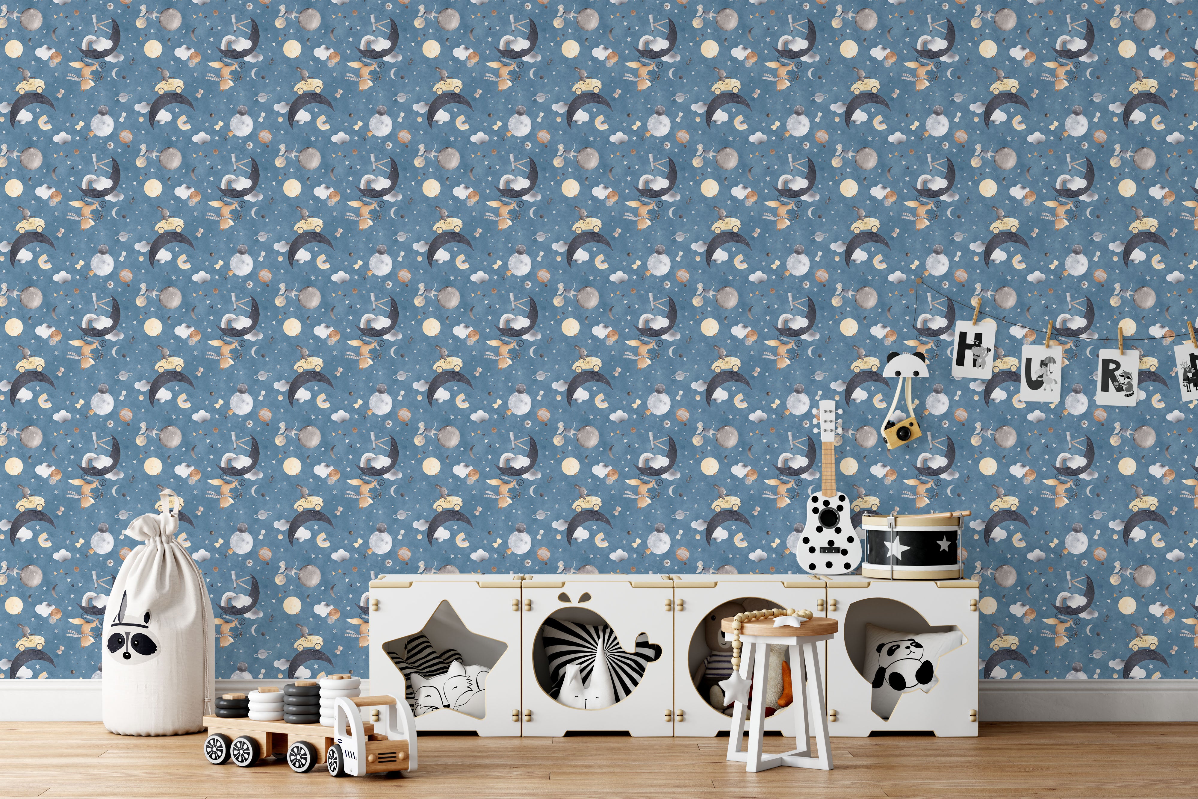 Whimsical wallpaper featuring watercolor rabbits driving cars and riding bikes on moons amidst stars, planets, and clouds on a blue background.
