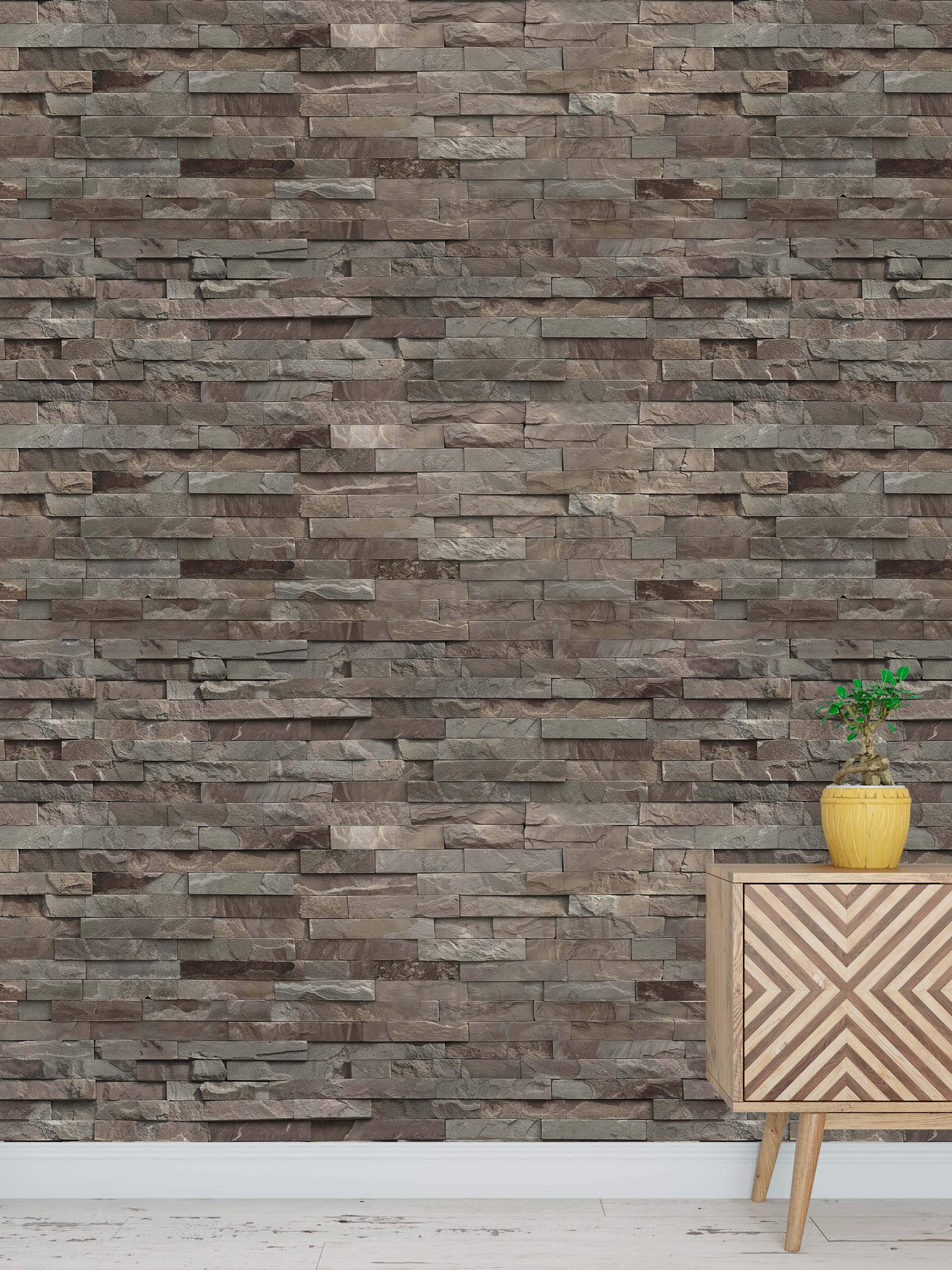 Wallpaper with a natural stacked ledger stone design featuring textured rectangular stones in brown and gray tones.