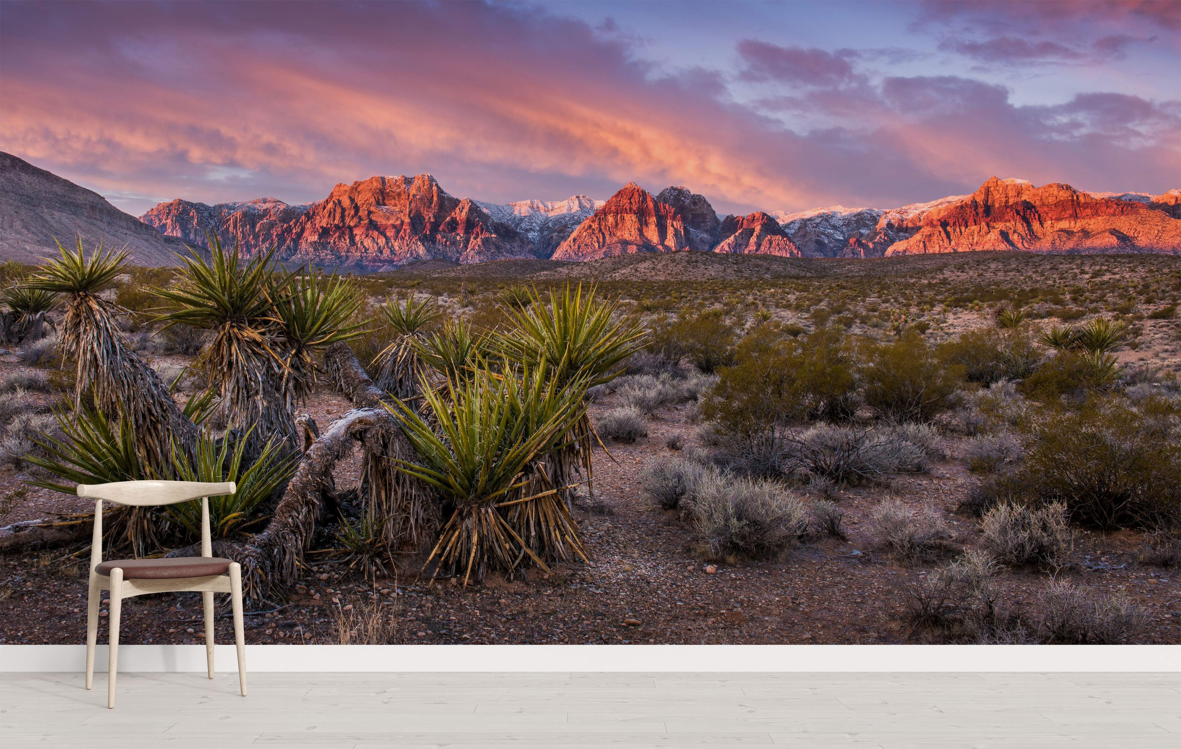 Mural featuring sunlit red rock mountains under a pink and purple sunset sky, above a desert floor with yucca plants.