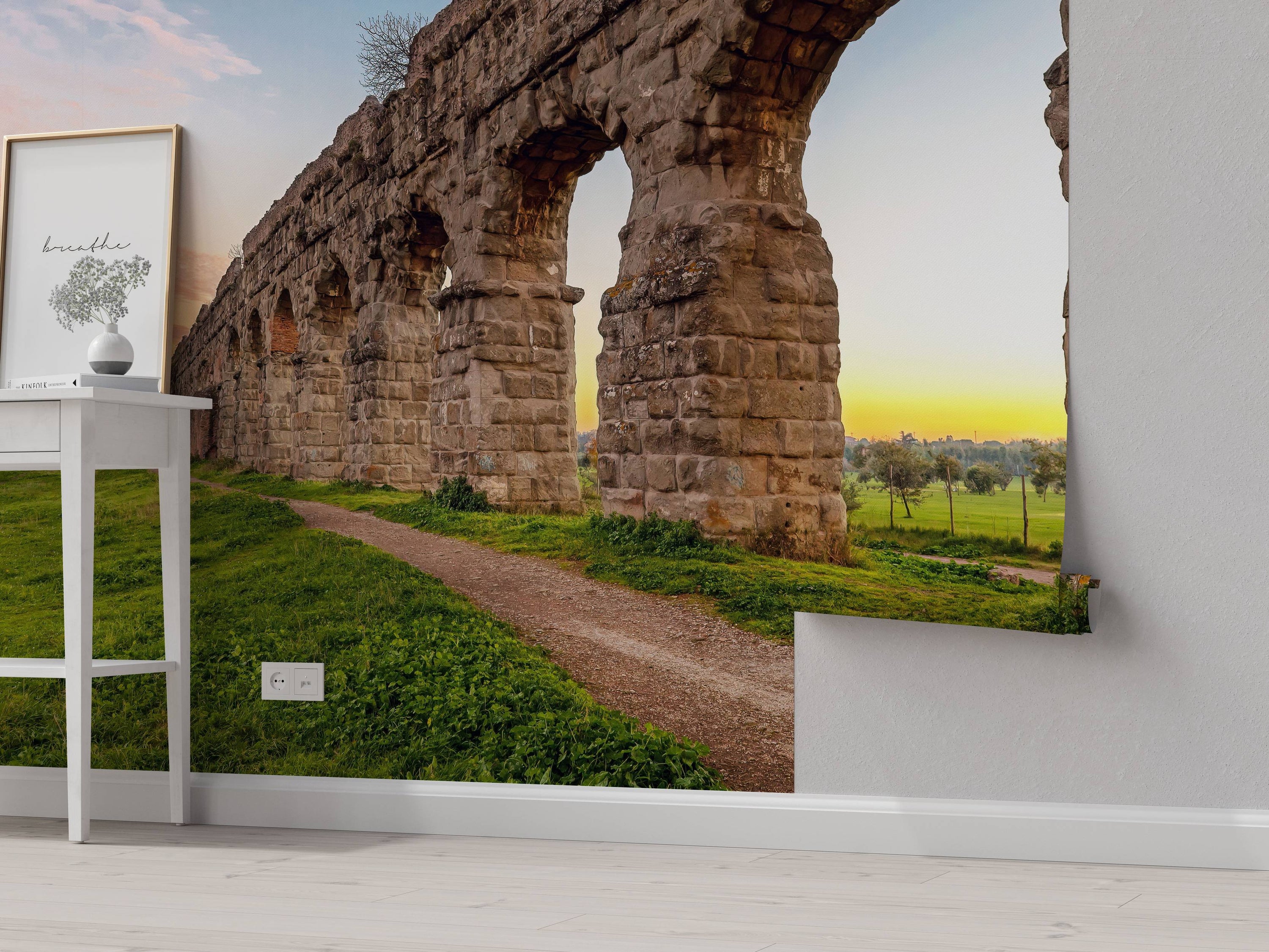 Mural of an ancient Roman aqueduct with large stone arches, set in a green landscape at sunset.