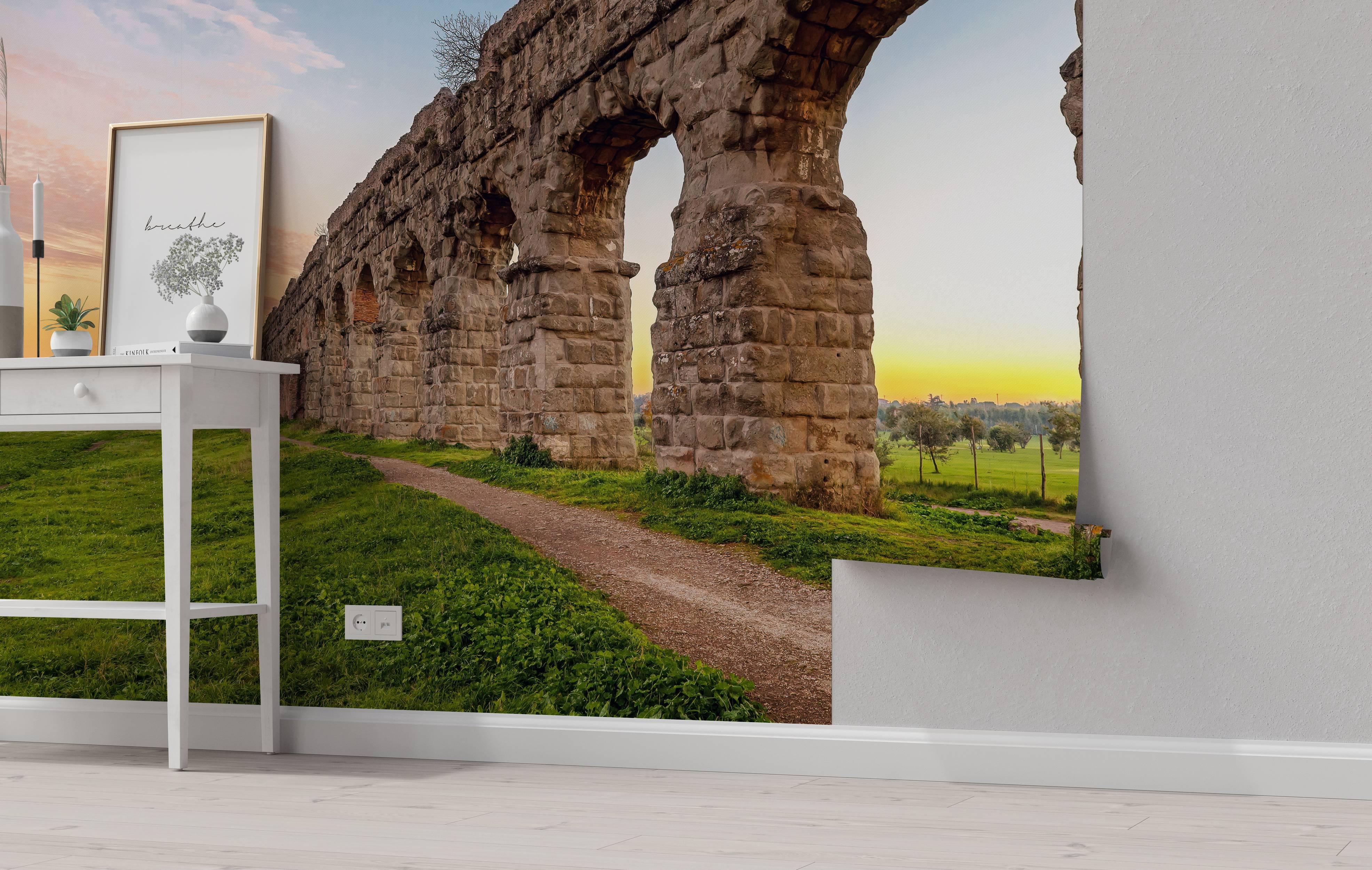Mural of an ancient Roman aqueduct with large stone arches, set in a green landscape at sunset.