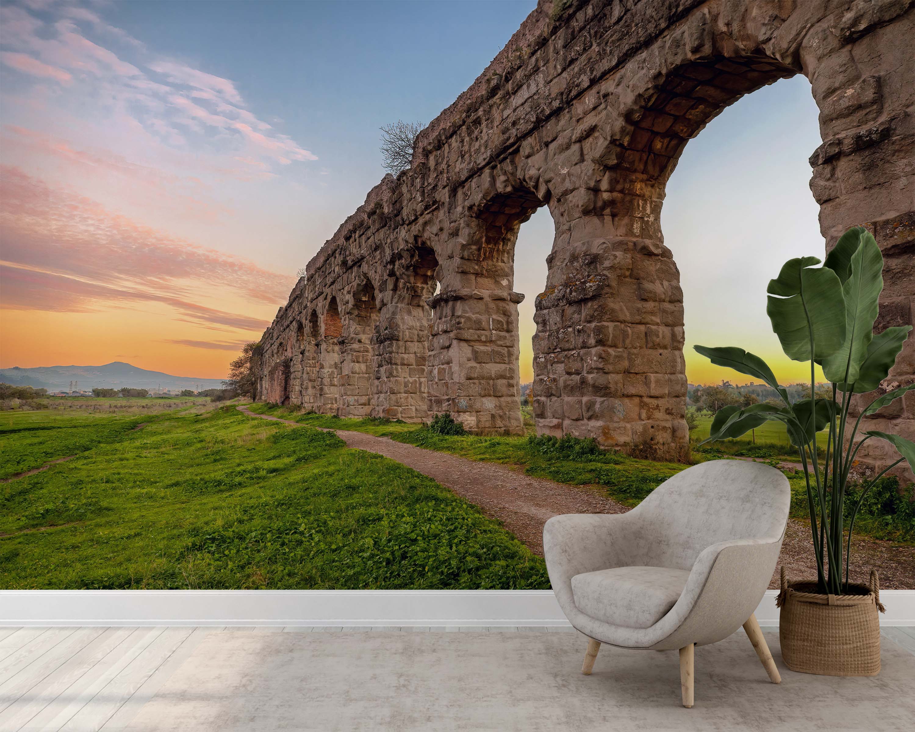 A wall mural of a Roman aqueduct at sunset, with stone arches stretching across a green field under a colorful sky.