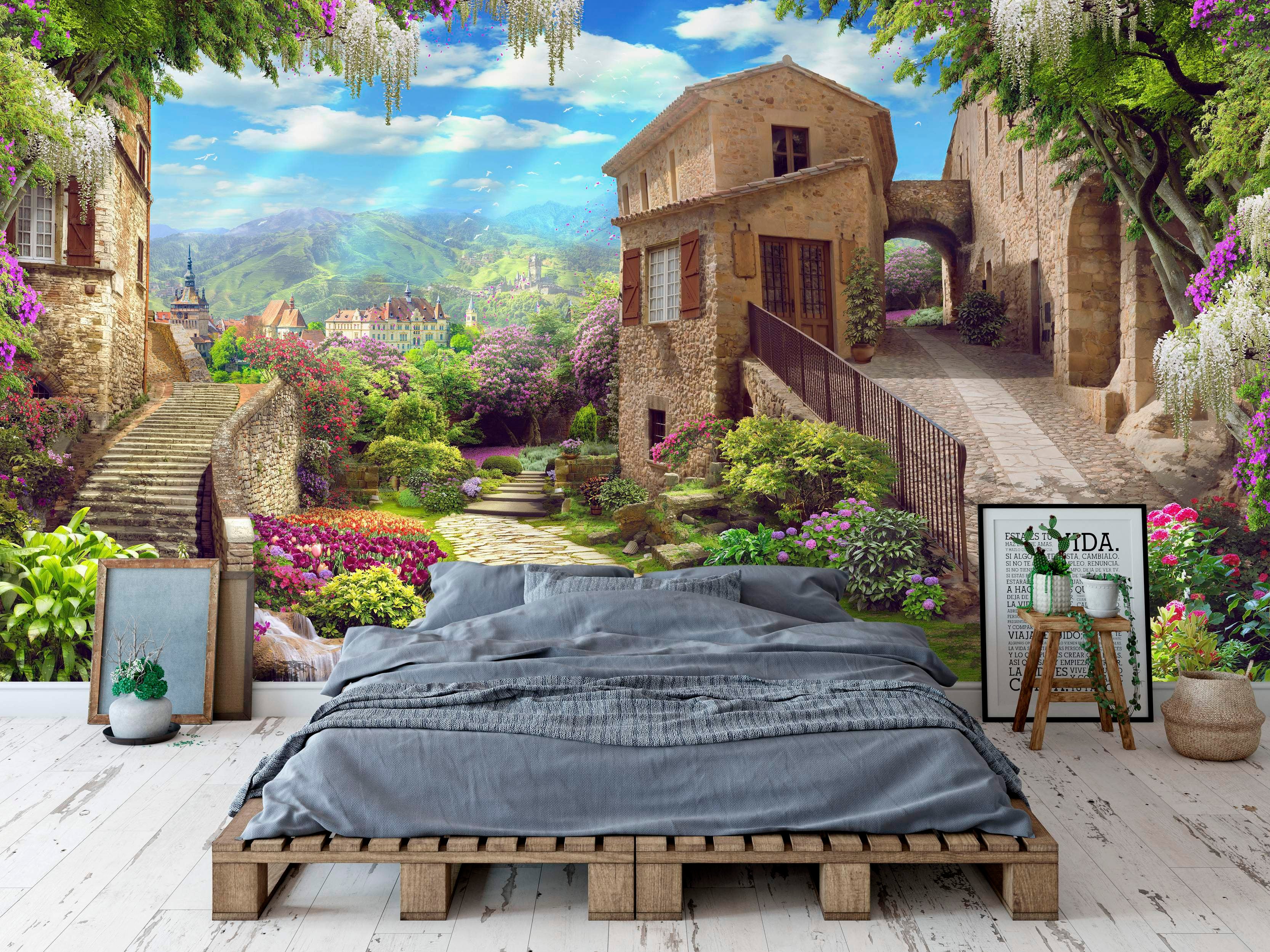 Scenic mural of a sunlit Italian village with stone buildings, cobblestone paths, stairs, vibrant flowers, and distant mountains.