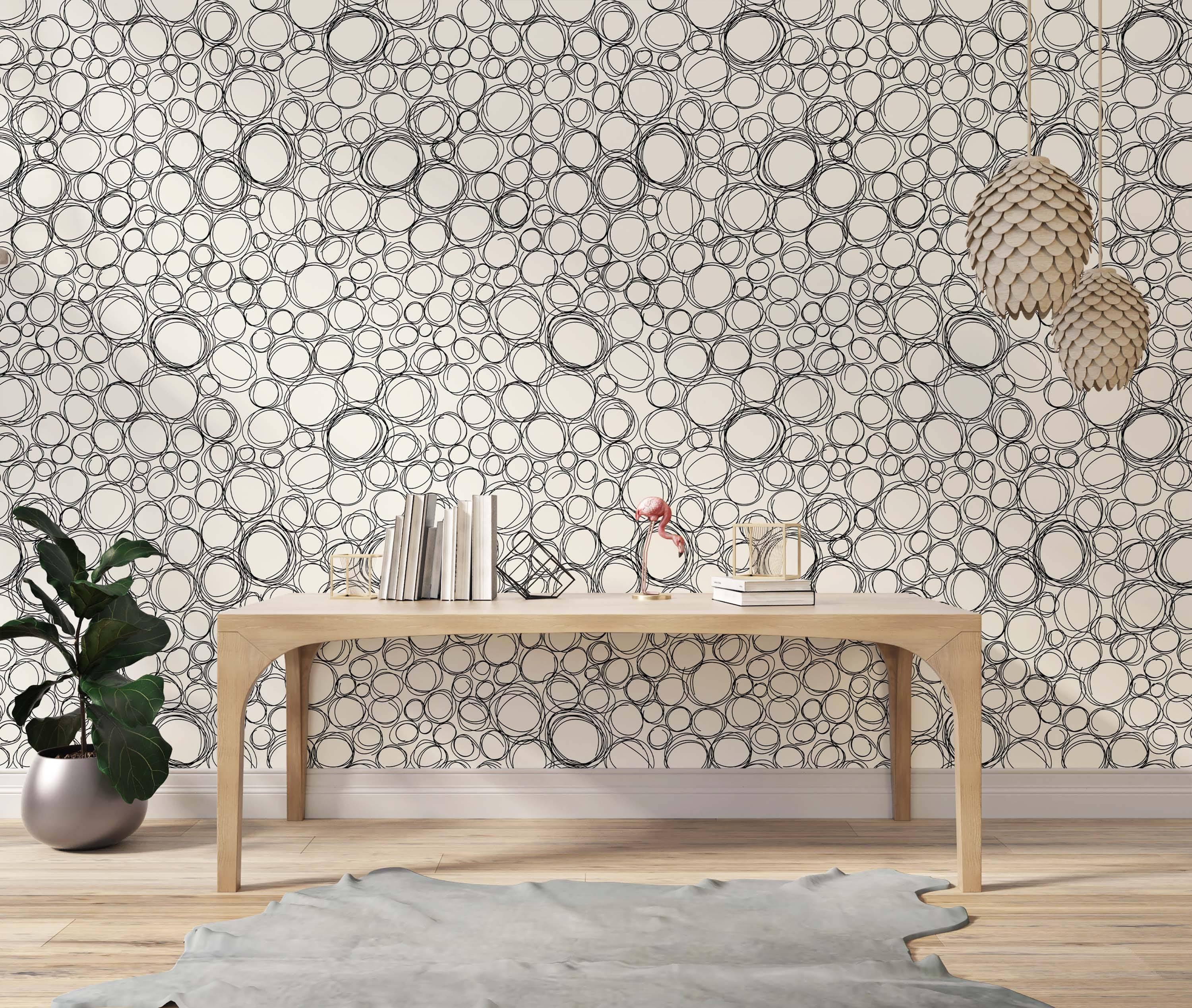 Wallpaper with a pattern of overlapping, hand-drawn black scribbled circles on an off-white background.