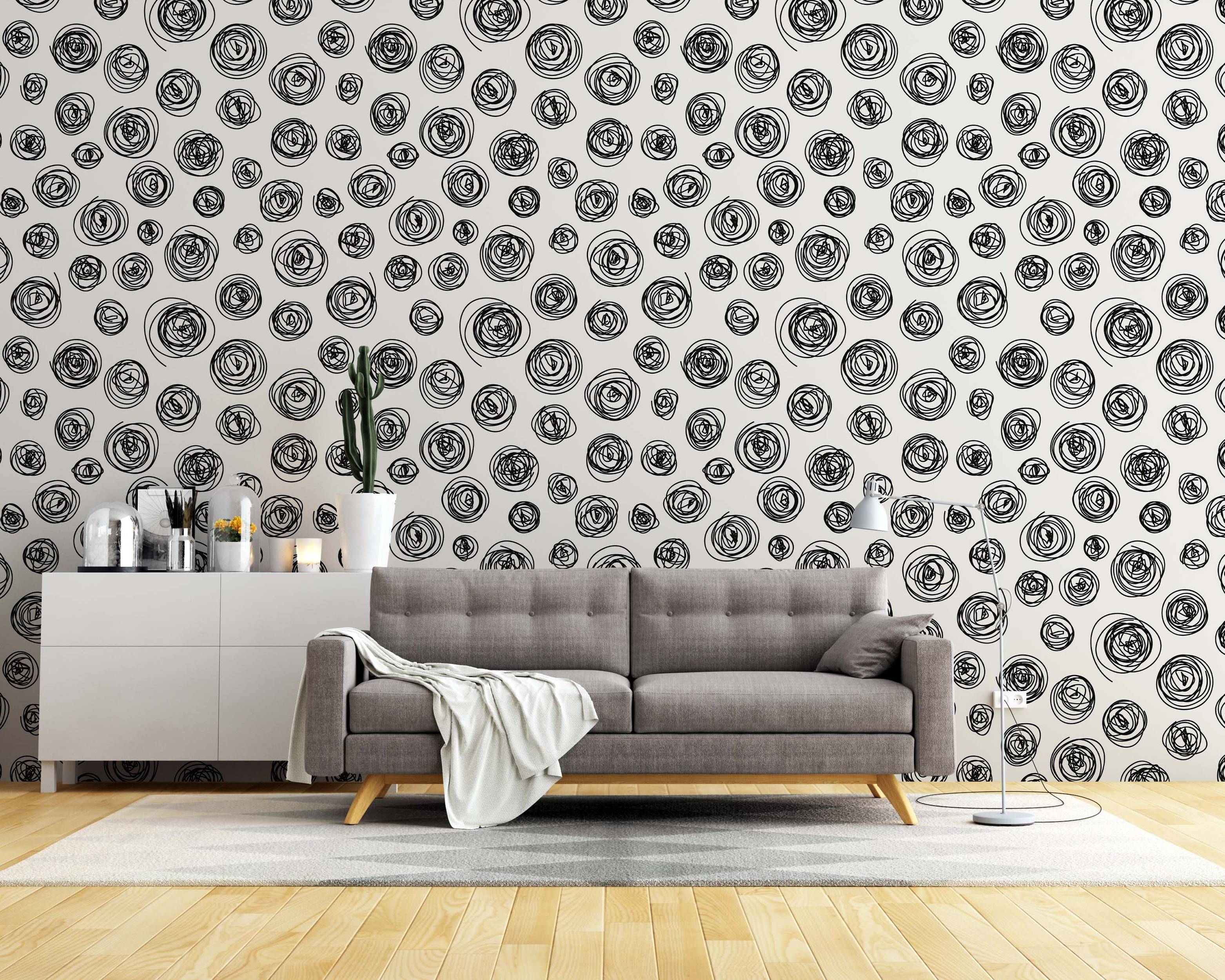 Wallpaper with a pattern of hand-drawn black scribbled circles in various sizes scattered on an off-white background.