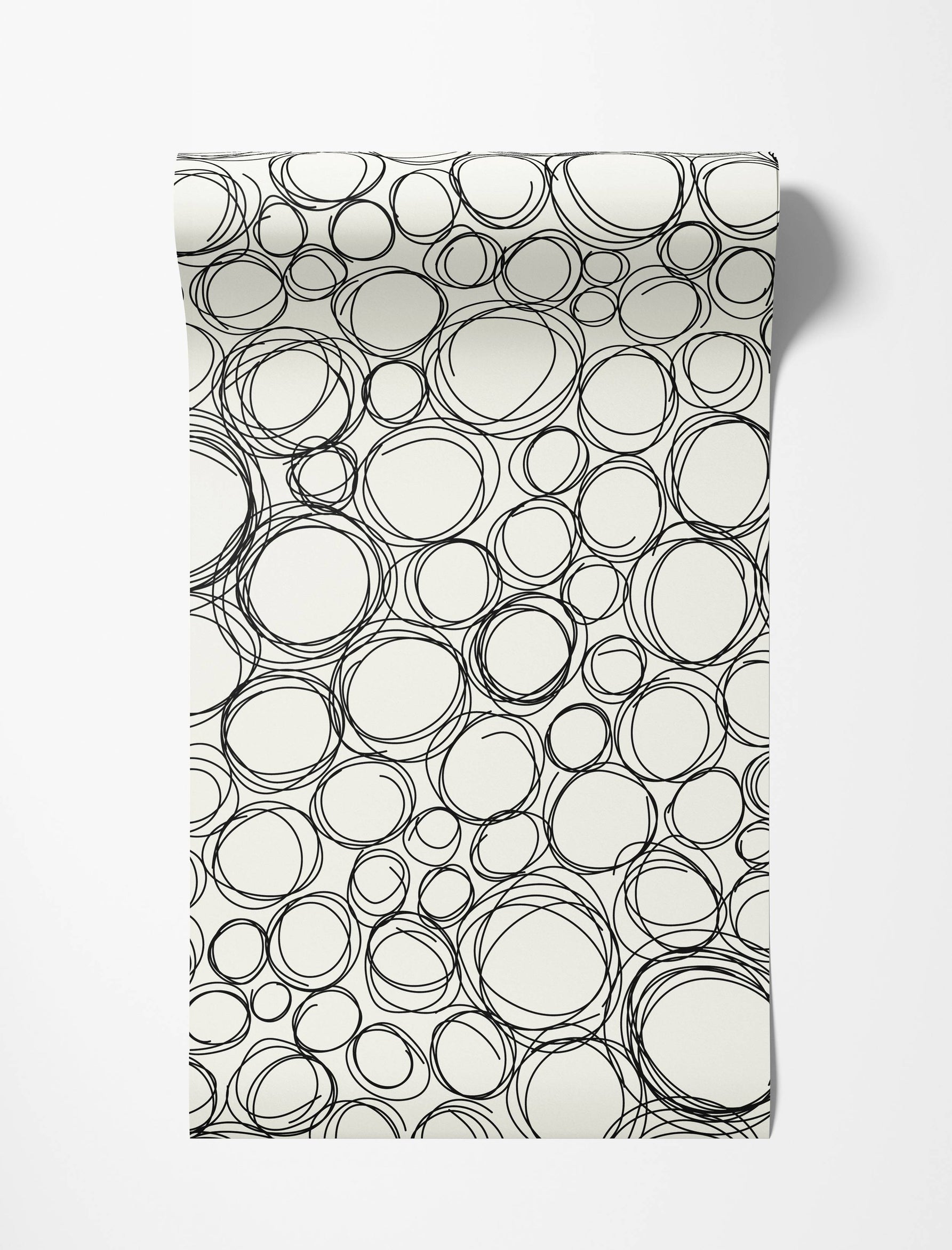 Wallpaper with a pattern of overlapping, hand-drawn black scribble circles and ovals on an off-white background.