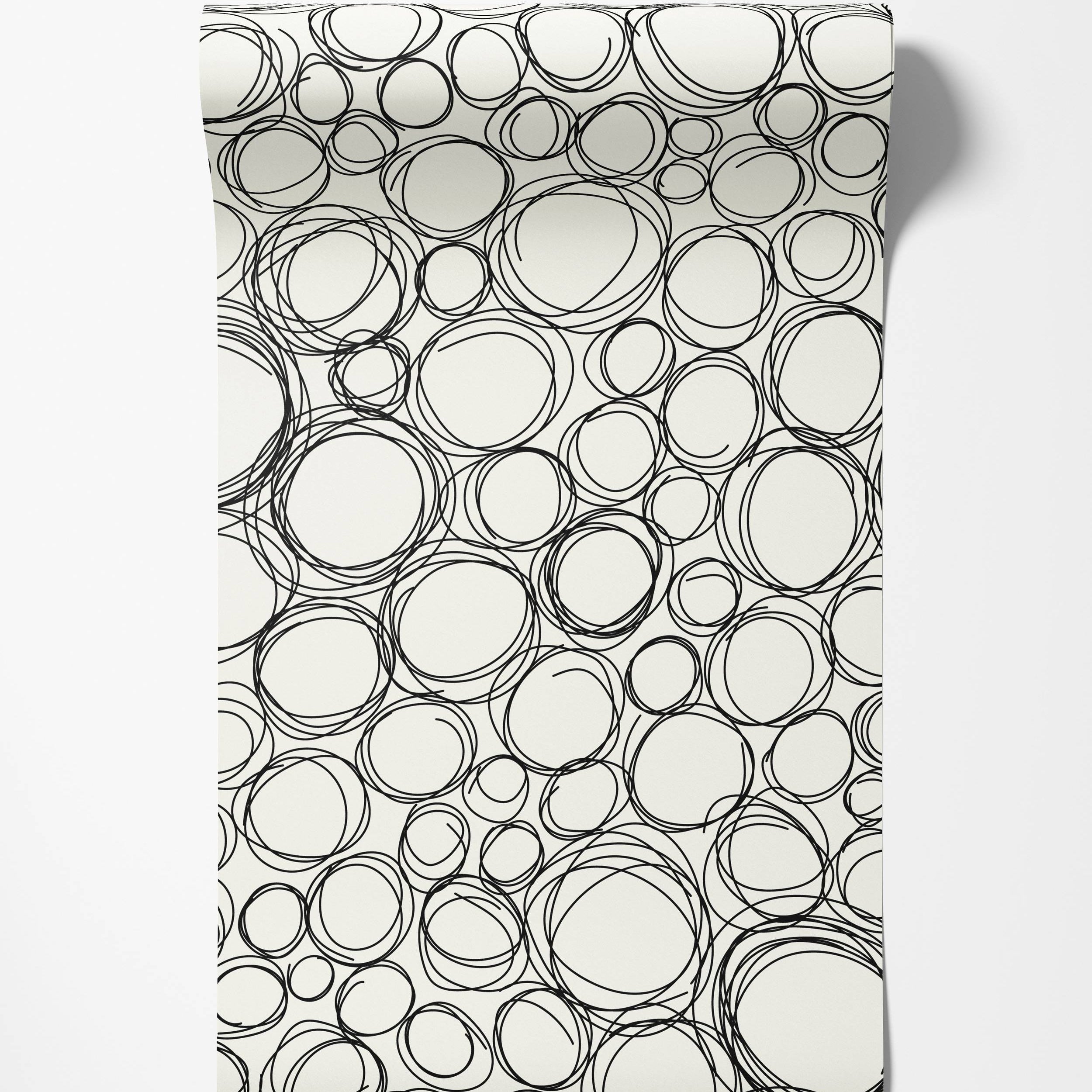 Wallpaper with a pattern of overlapping, hand-drawn black scribble circles and ovals on an off-white background.