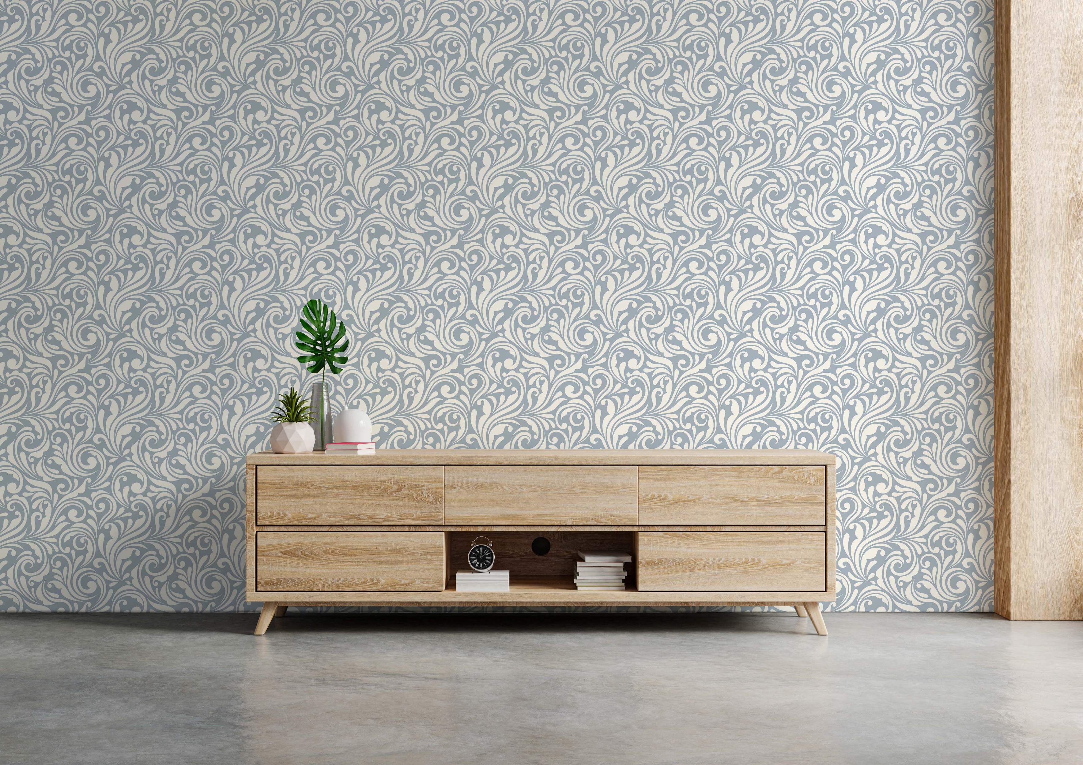 Cream swirling vine and leaf scrollwork pattern on a muted blue-gray background wallpaper.