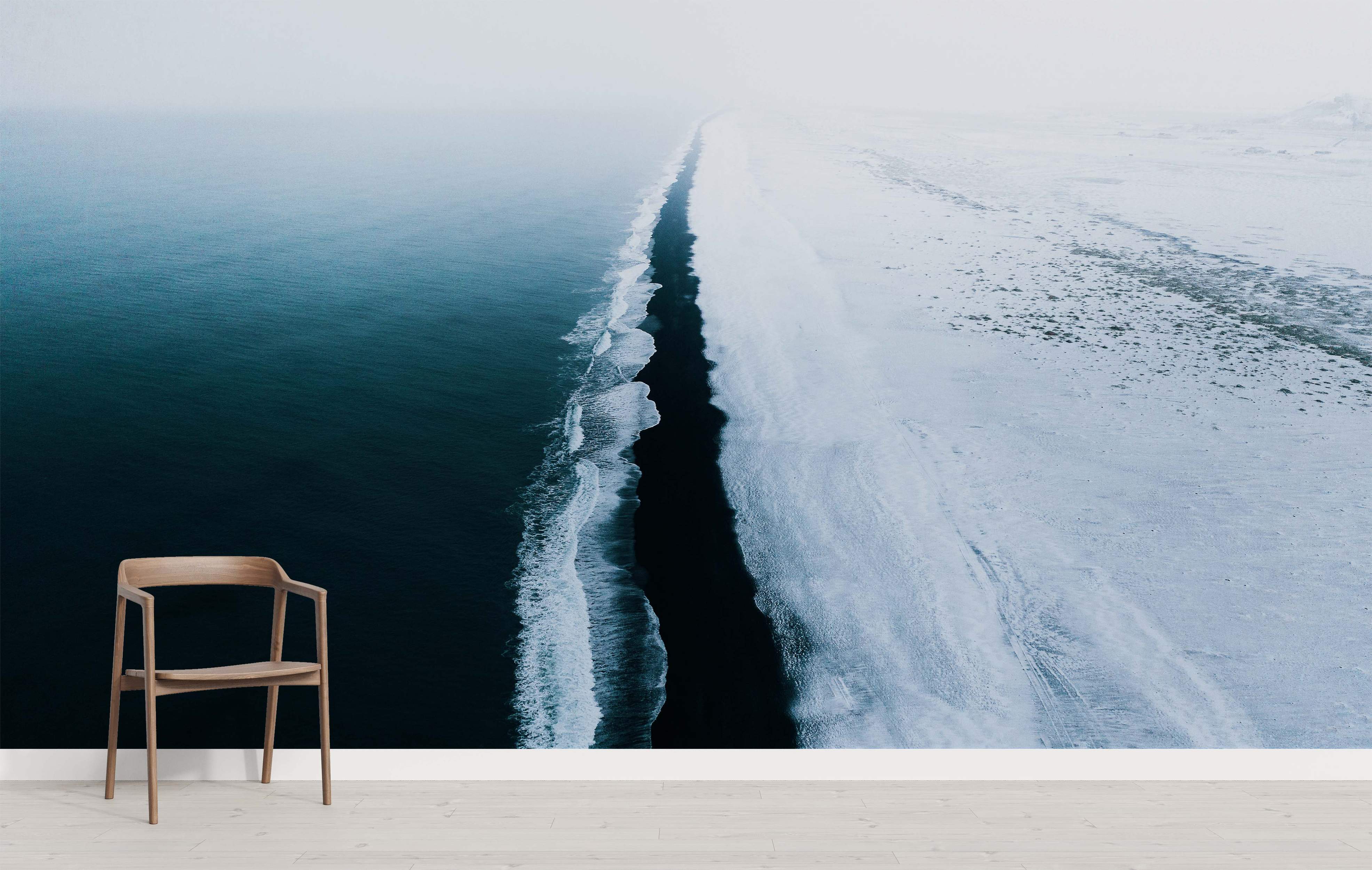 Mural depicting an aerial view of a snowy black sand beach meeting dark blue ocean waves under a misty sky.