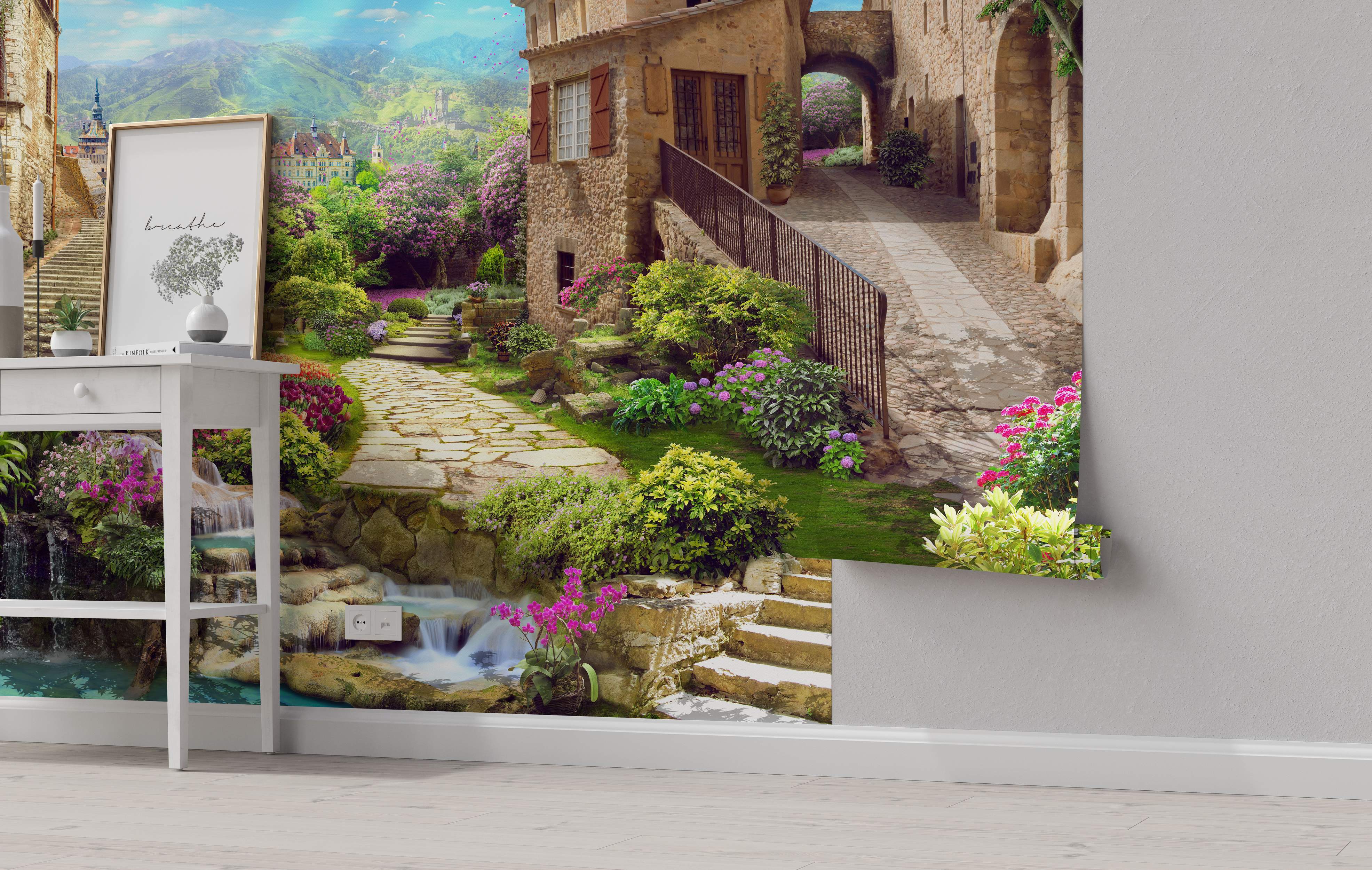Mural depicting a charming European stone village street with gardens, flowers, a waterfall, and mountain scenery.
