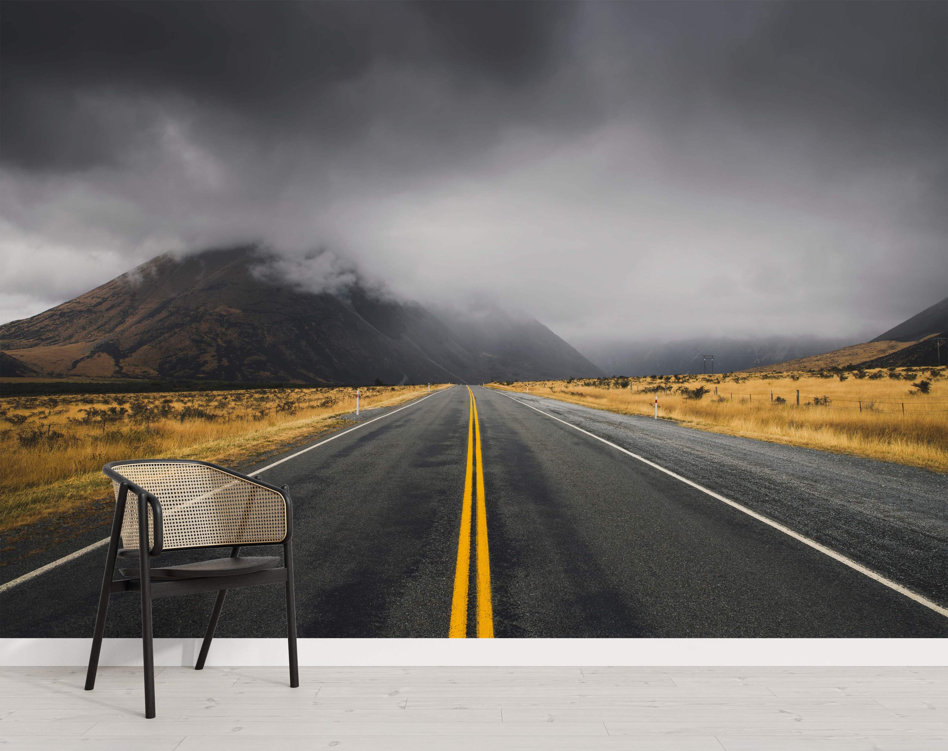 A stormy mountain landscape mural with a road and cloudy skies.